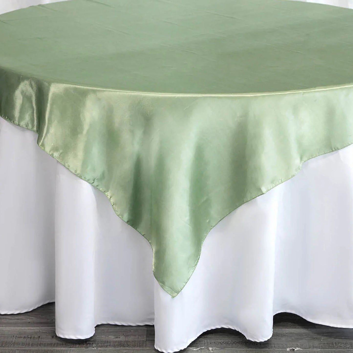 Sage green satin square tablecloth overlay on a white table.