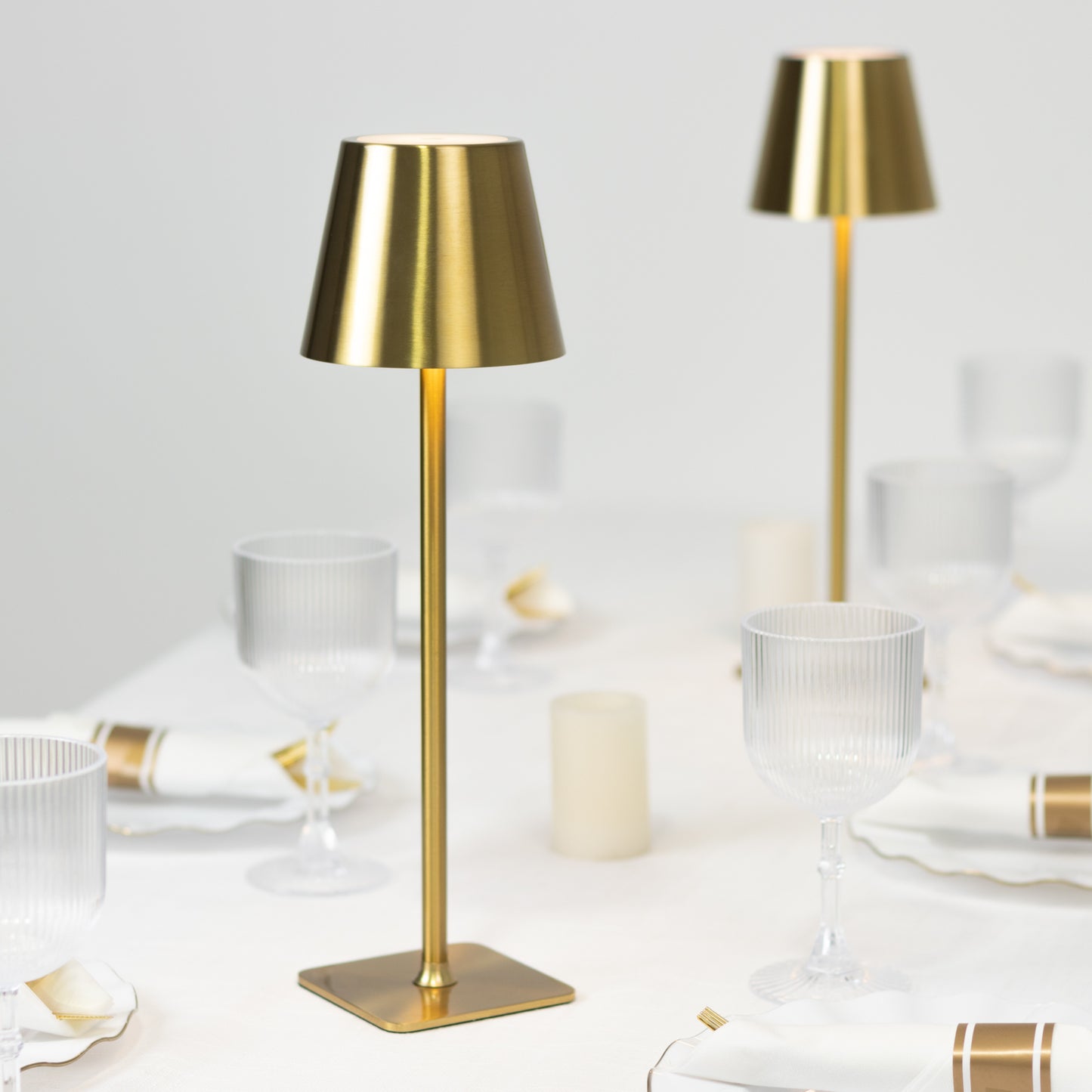 Gold metal LED table lamp with classic empire lampshade on a dining table.