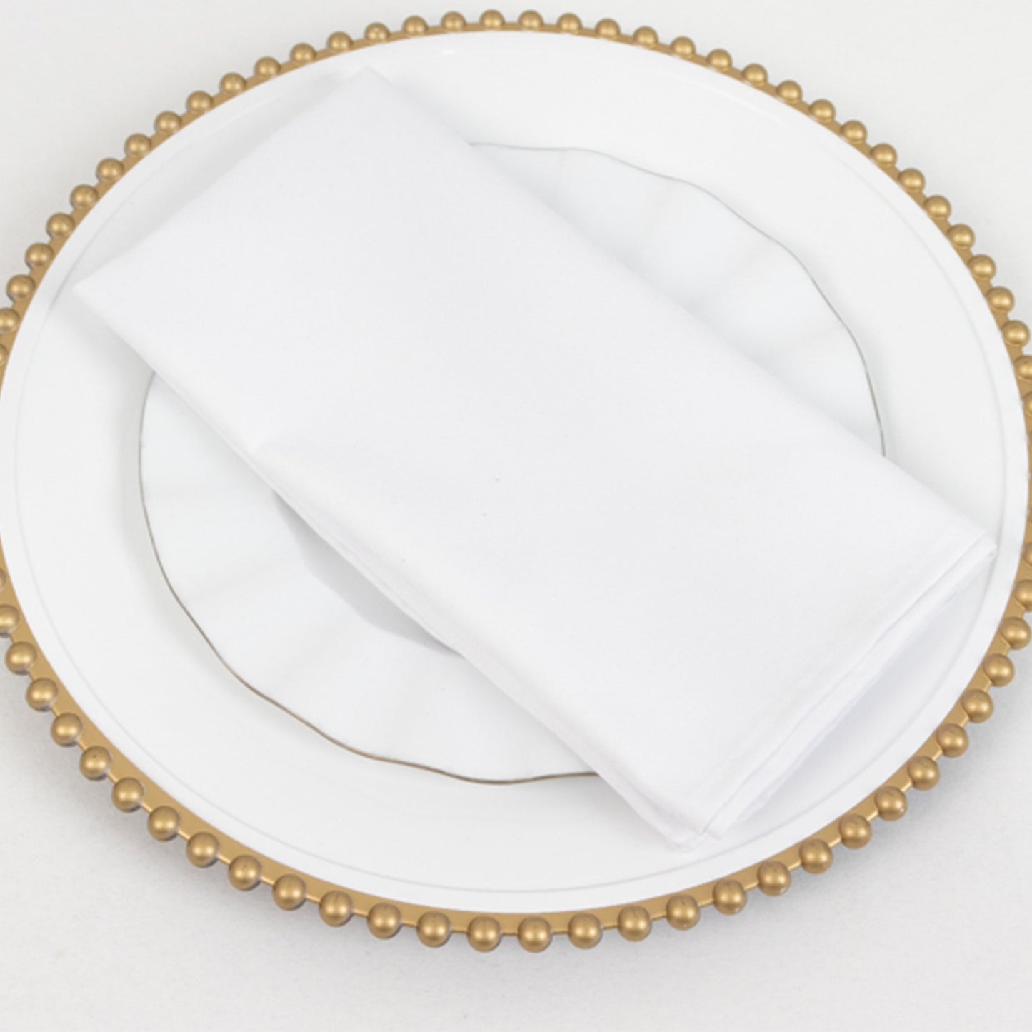 White cotton blend cloth napkin on a decorative plate.