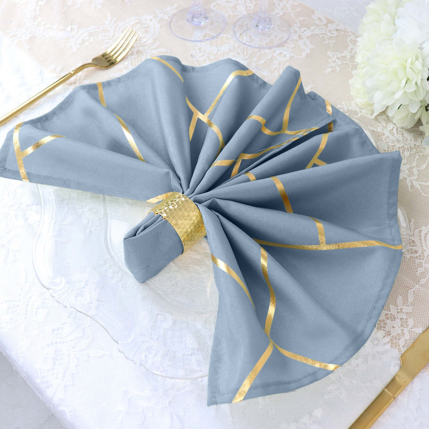 Modern dusty blue and geometric gold dinner napkin on a table setting.