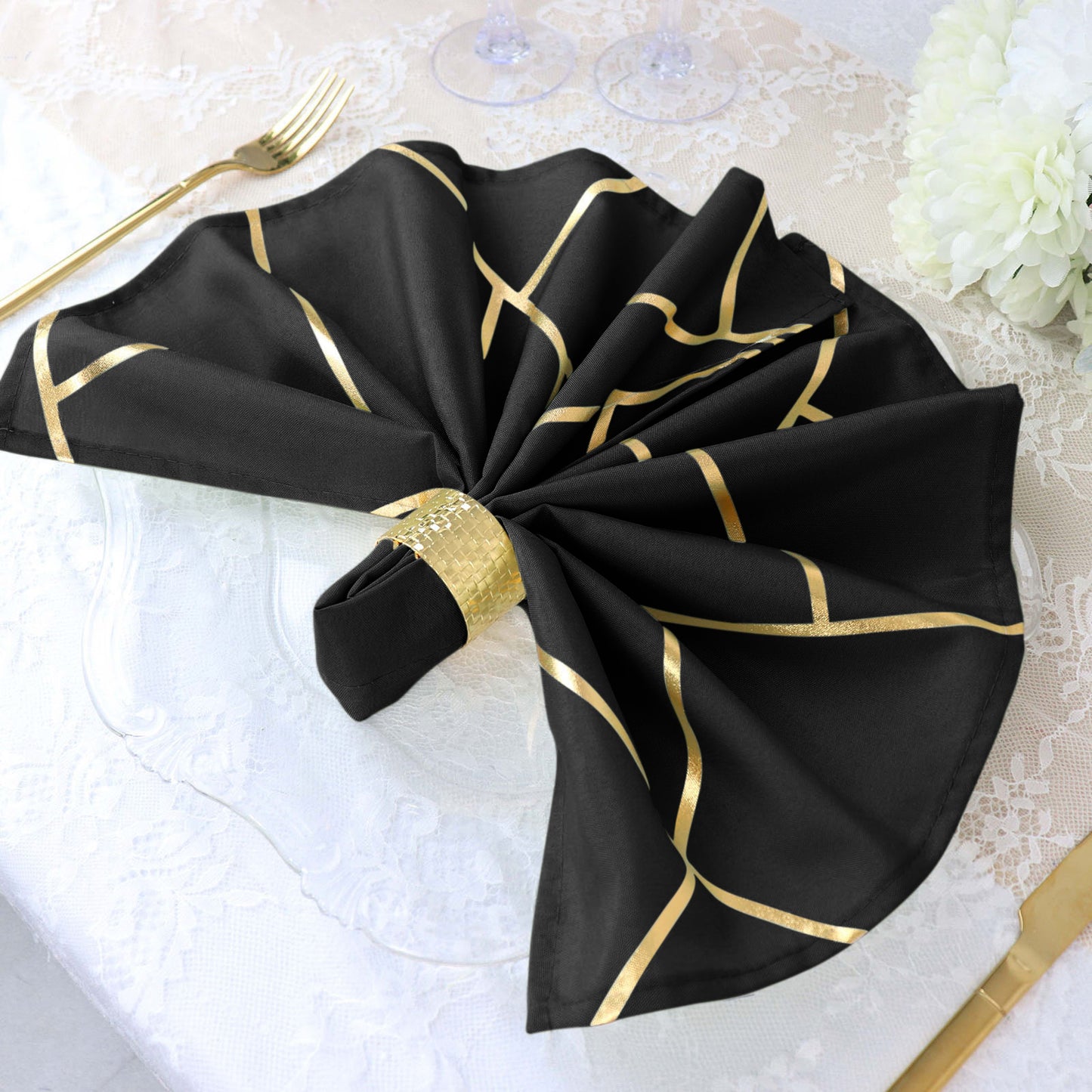 Modern black and geometric gold dinner napkin on a table setting.