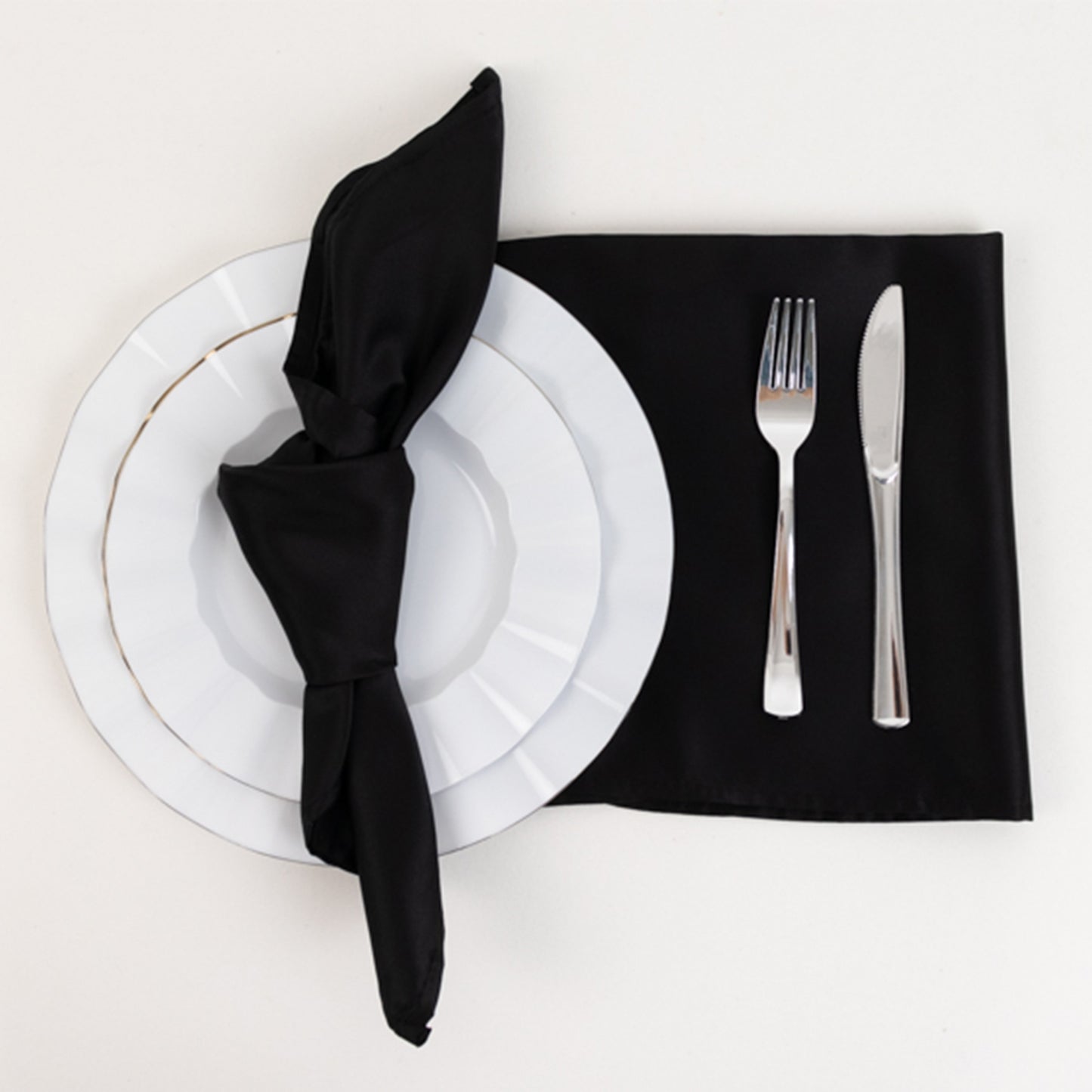 Black satin napkin elegantly displayed on a plate next to cutlery.