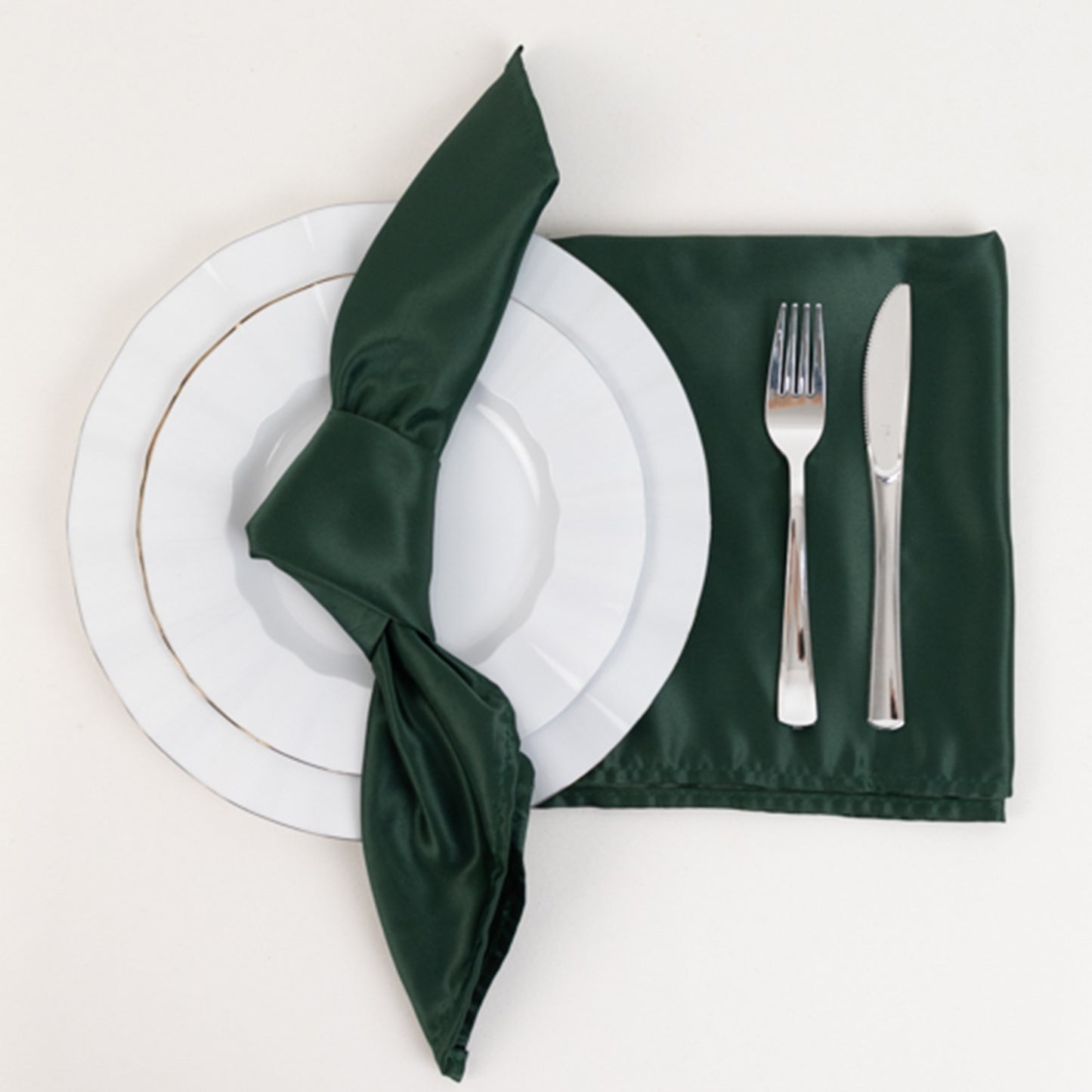 Hunter Emerald Green satin napkin on a plate with silverware.