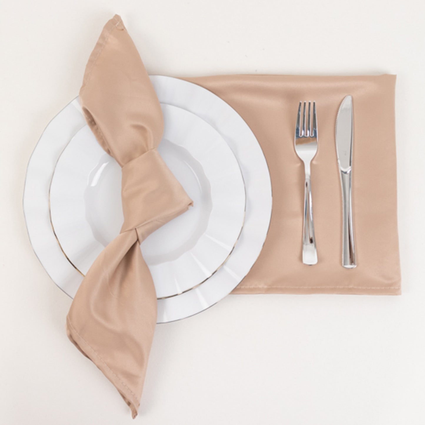 Nude satin napkins arranged with a plate, fork, and knife.