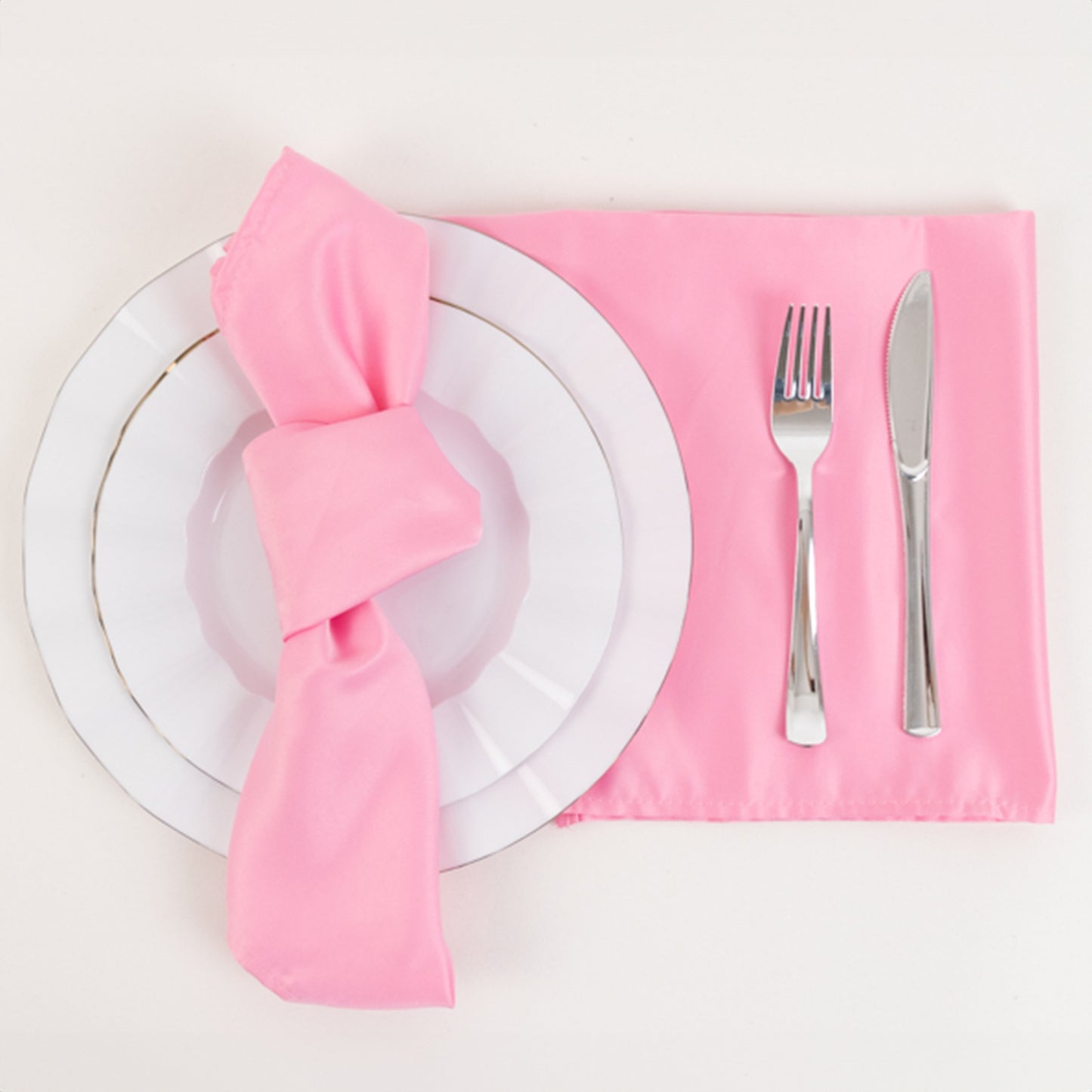 Pink satin napkins on a table setting with a plate and utensils.