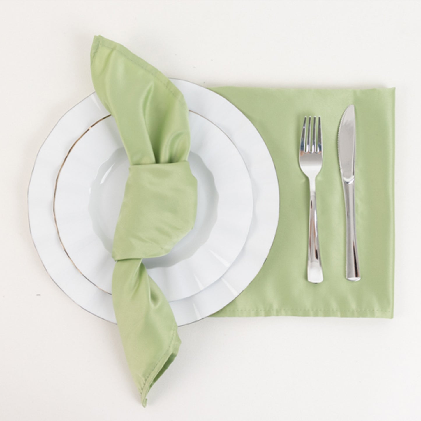 Sage green satin napkins styled on a plate setting.
