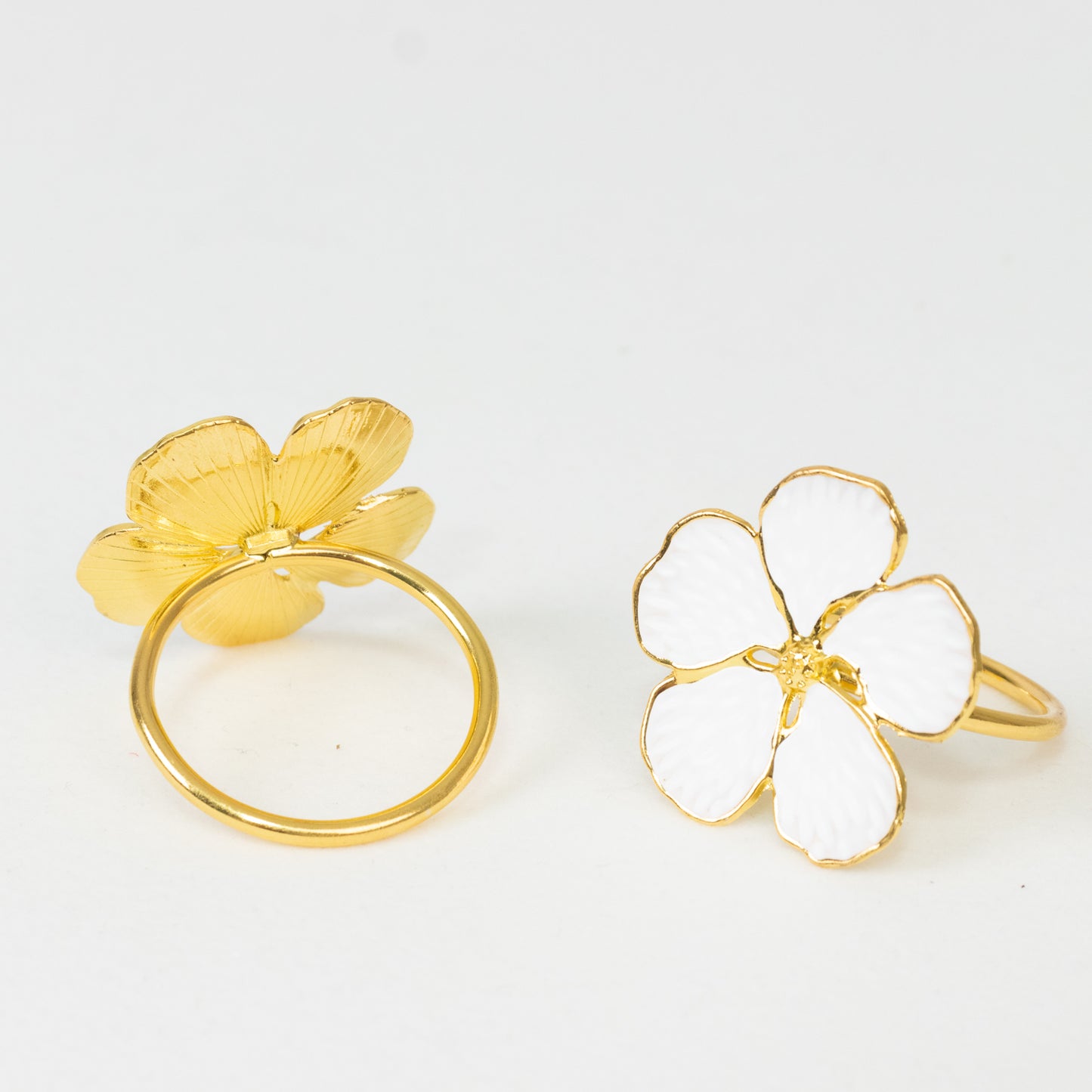 White and gold metal flower napkin rings in plum blossom design.