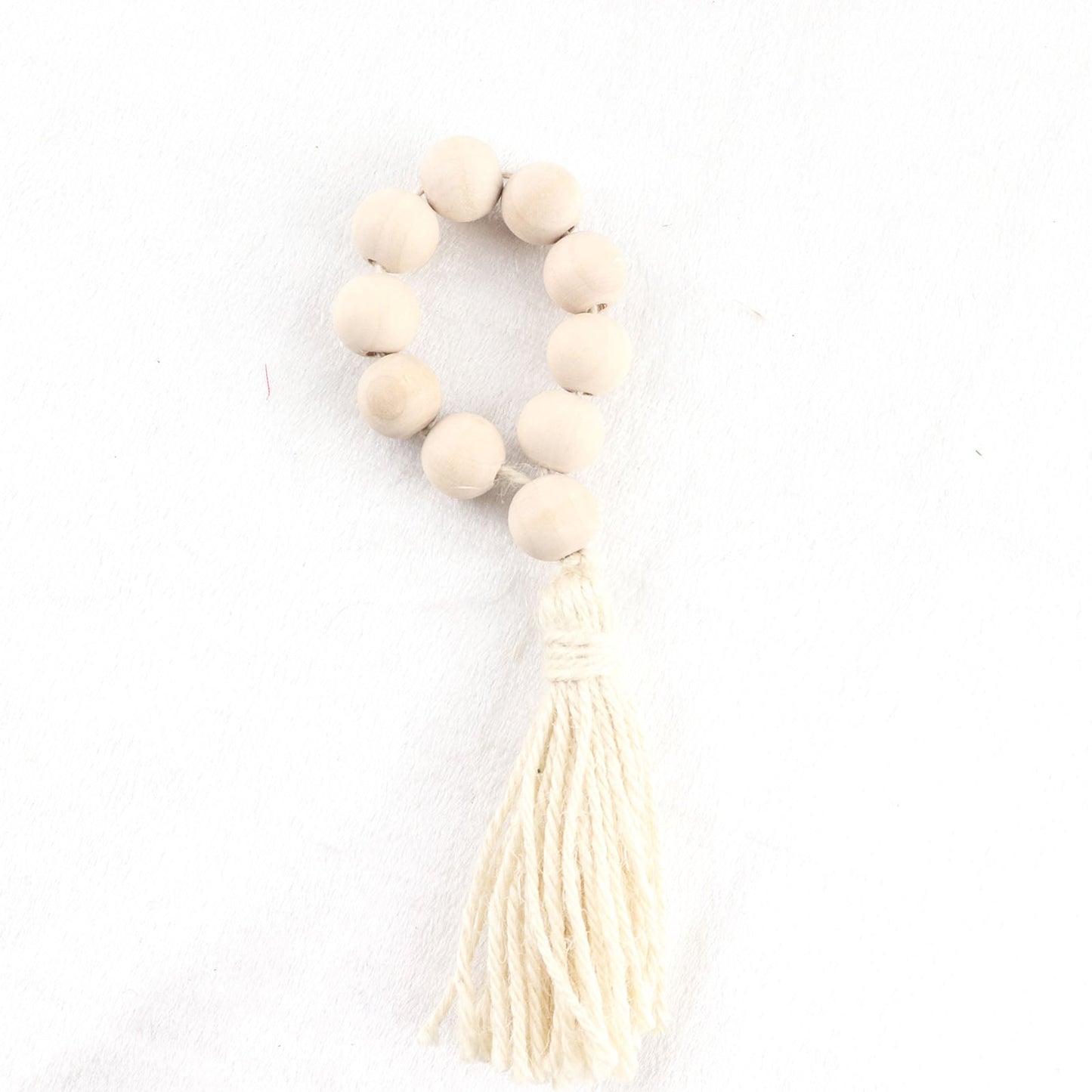 Cream wood bead napkin ring with tassel, rustic boho chic decor.