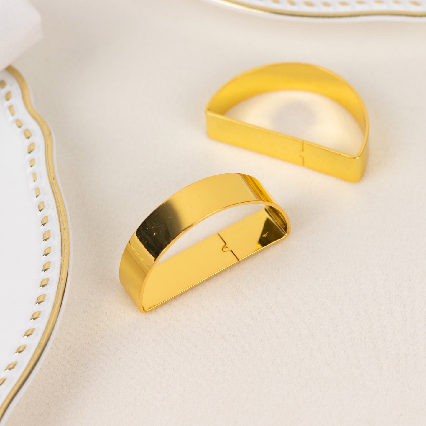 Shiny gold semicircle napkin rings for elegant table settings.