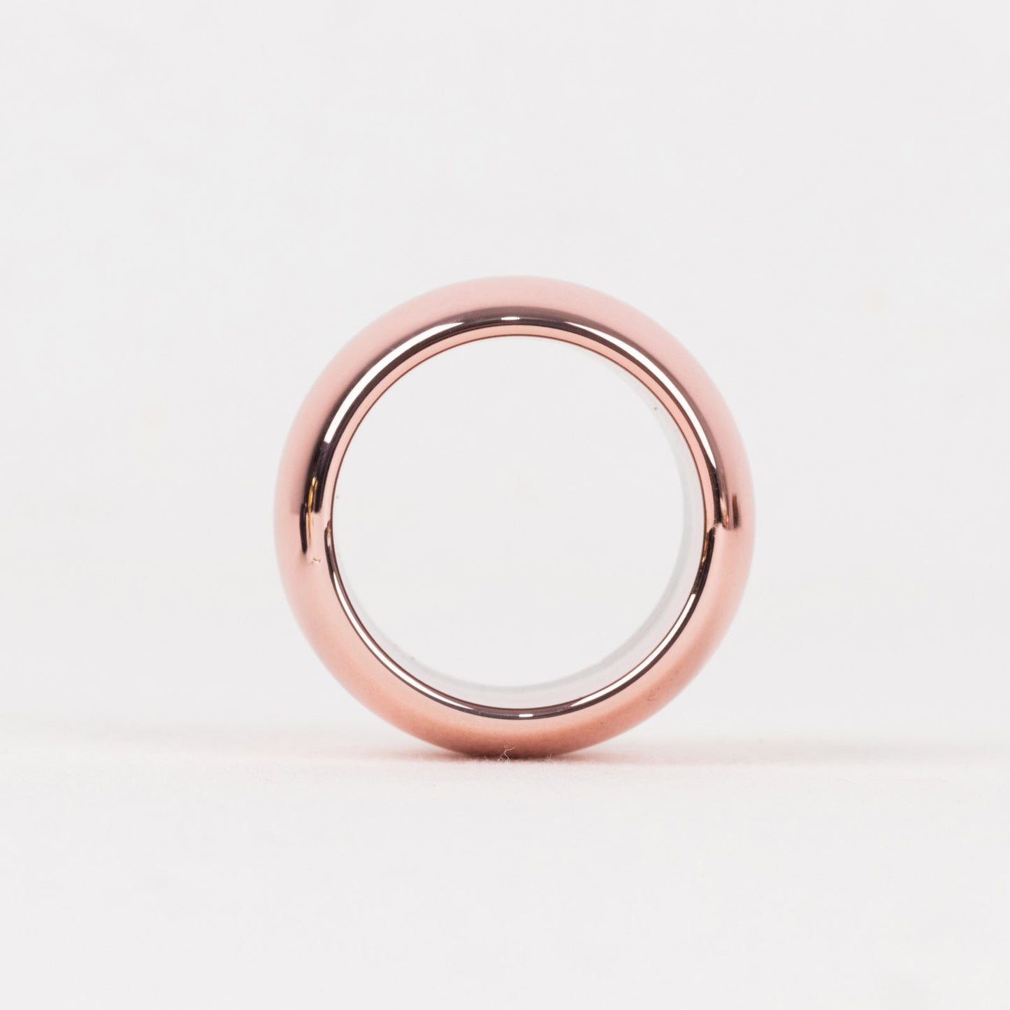 Shiny metallic rose gold acrylic napkin ring on a white background.