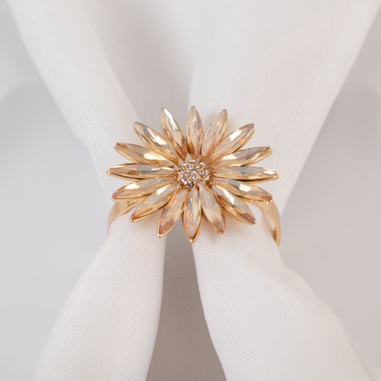 Amber gold floral napkin ring with rhinestone accents on a white napkin.
