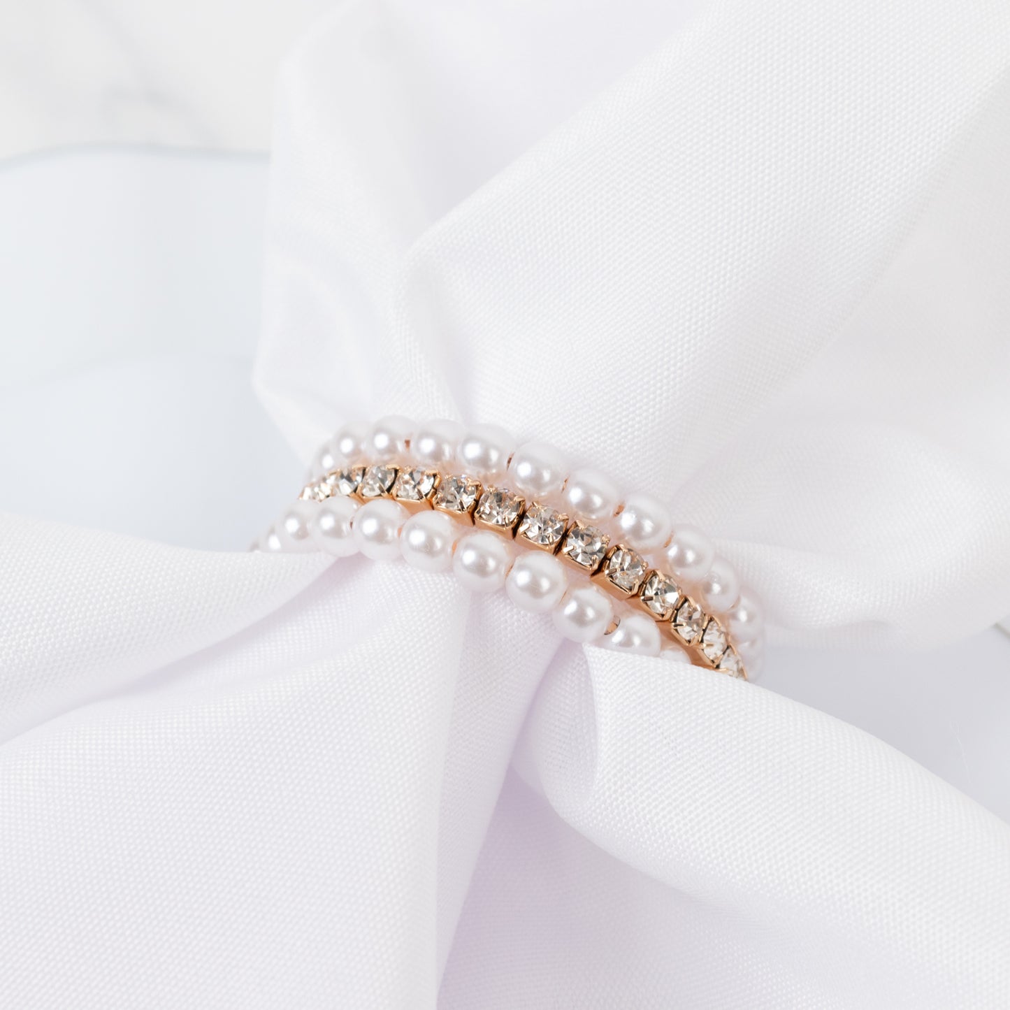 White pearl rhinestone napkin holders elegantly displayed with a white napkin.