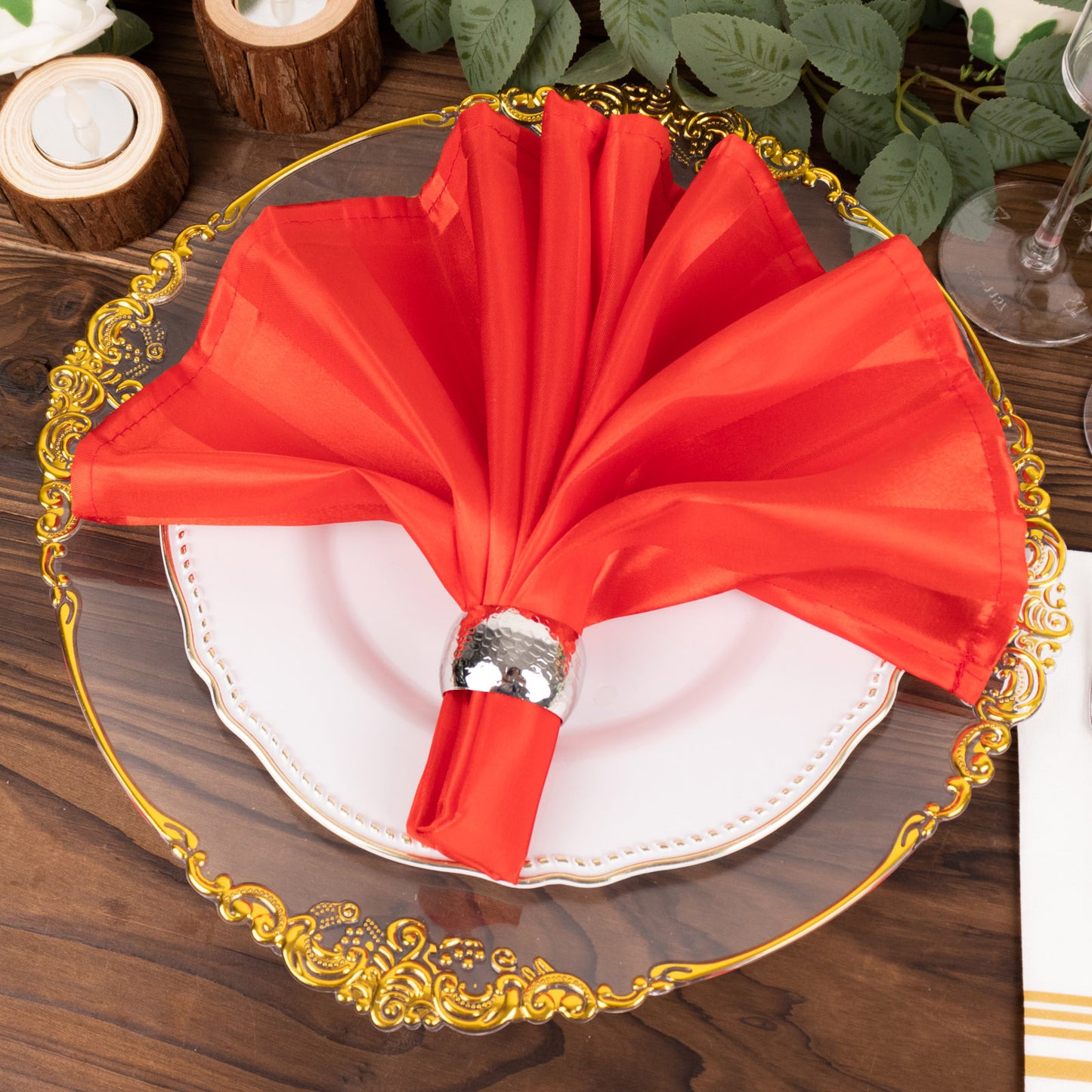Red satin napkin elegantly displayed on a decorative plate.