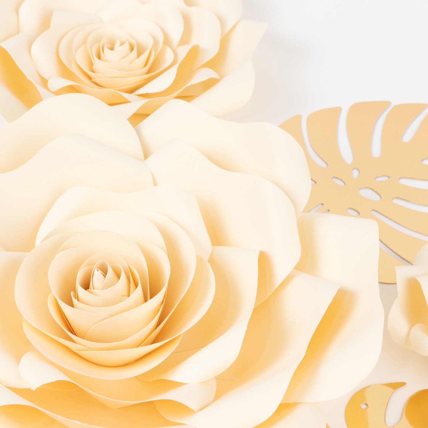 Ivory 3D rose paper flowers with gold tropical palm leaves for decor.