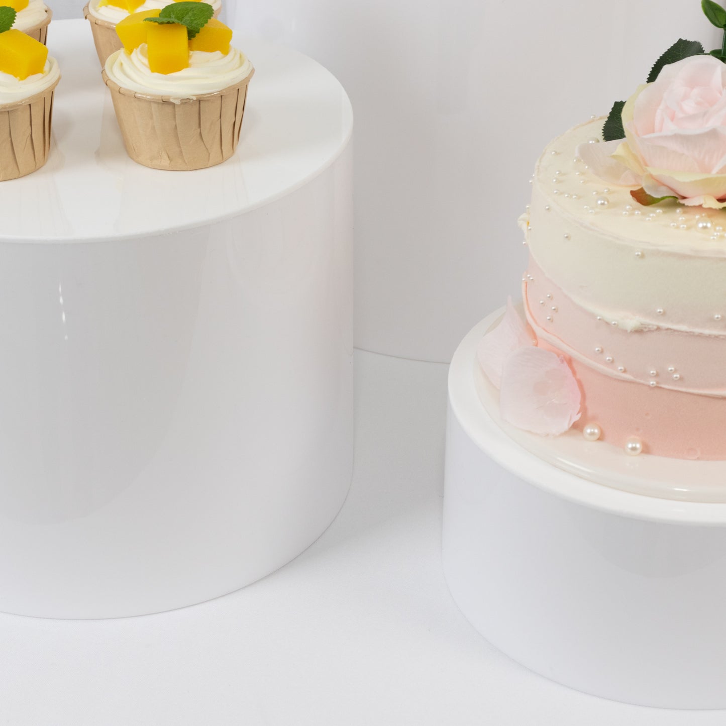 White acrylic cake stands in various sizes for event displays.