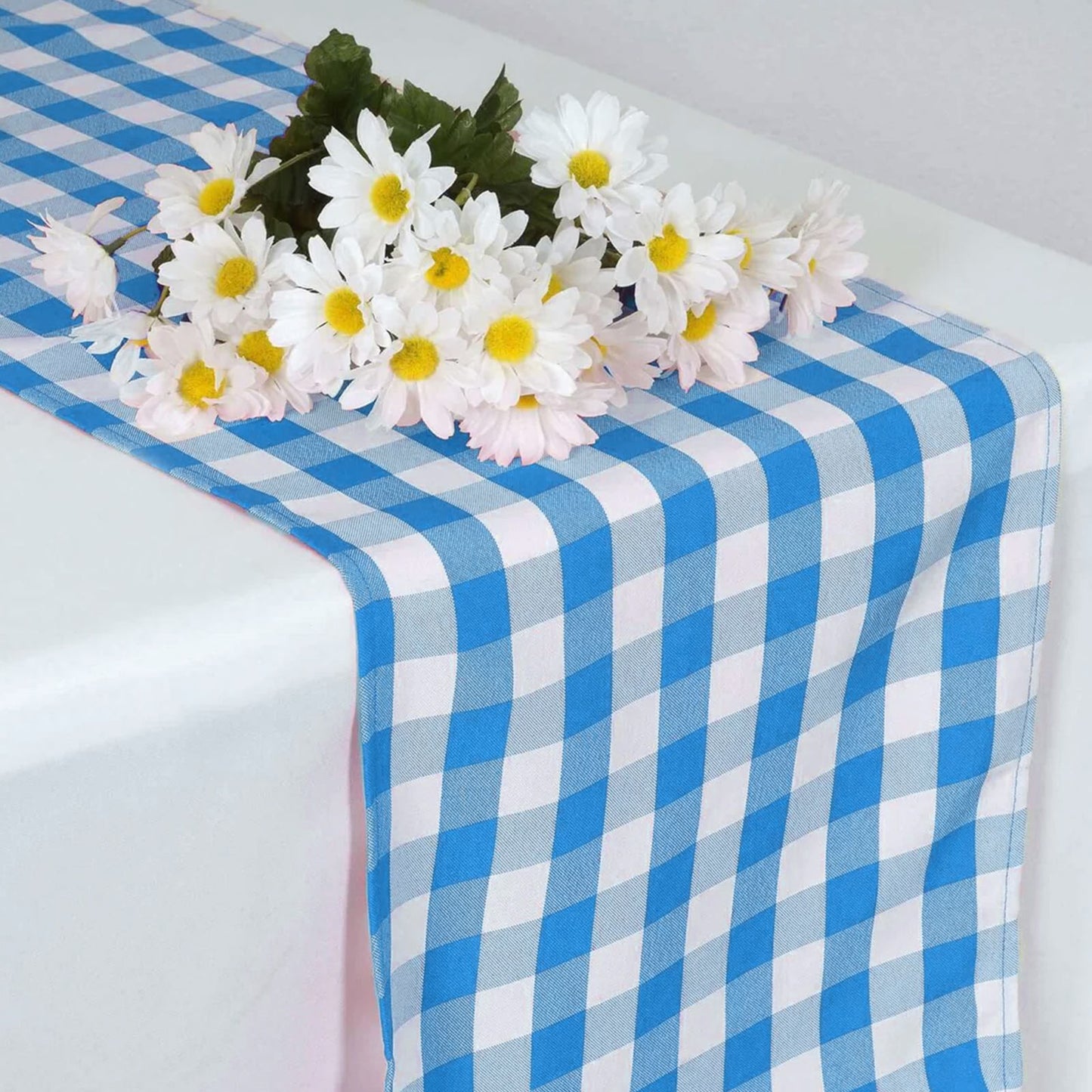 Blue and white gingham table runner with flowers on top.
