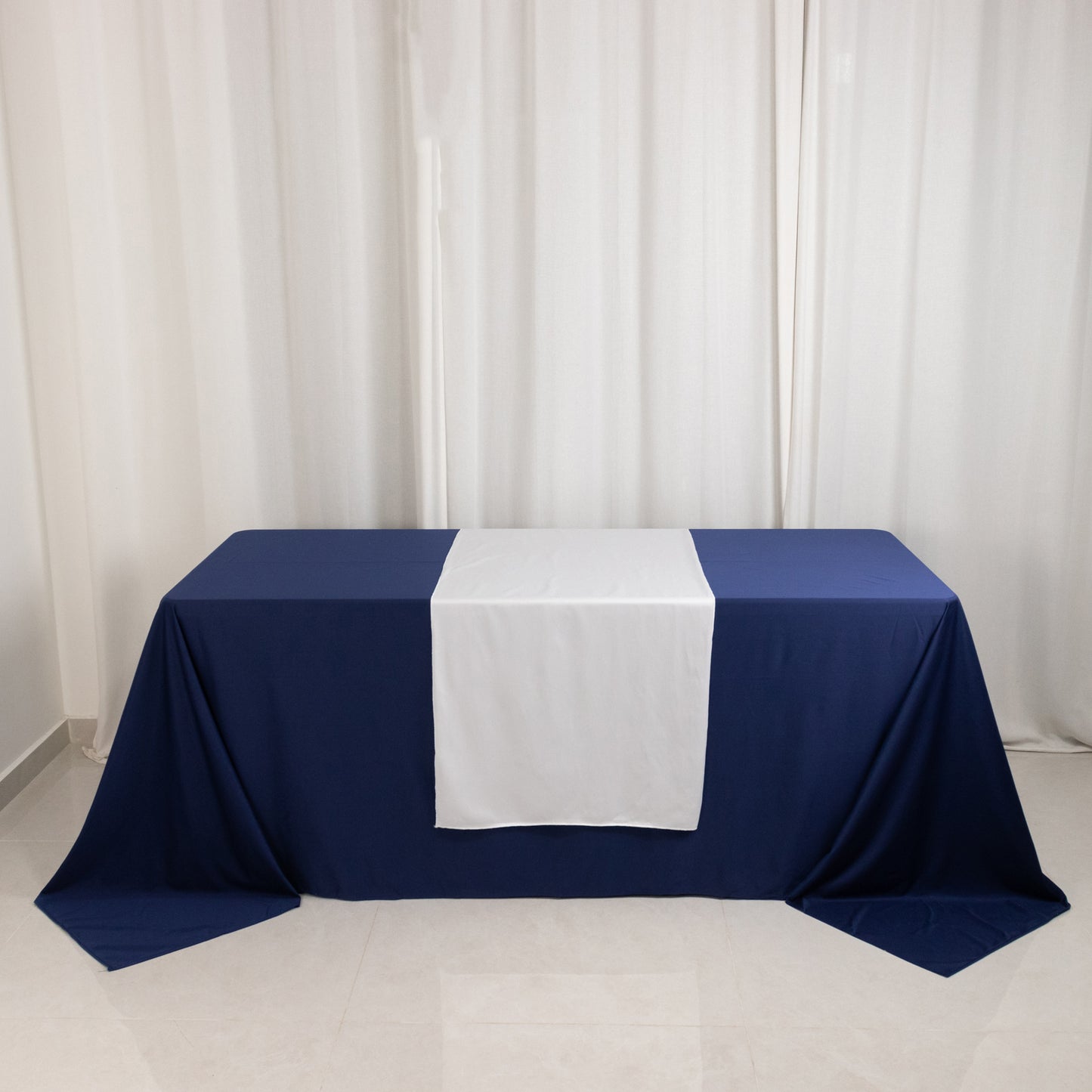 White polyester table runner on a navy blue table at a trade show.