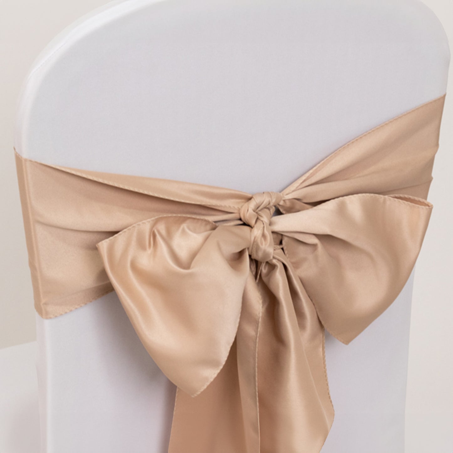 Nude satin chair sash bow on a white chair.