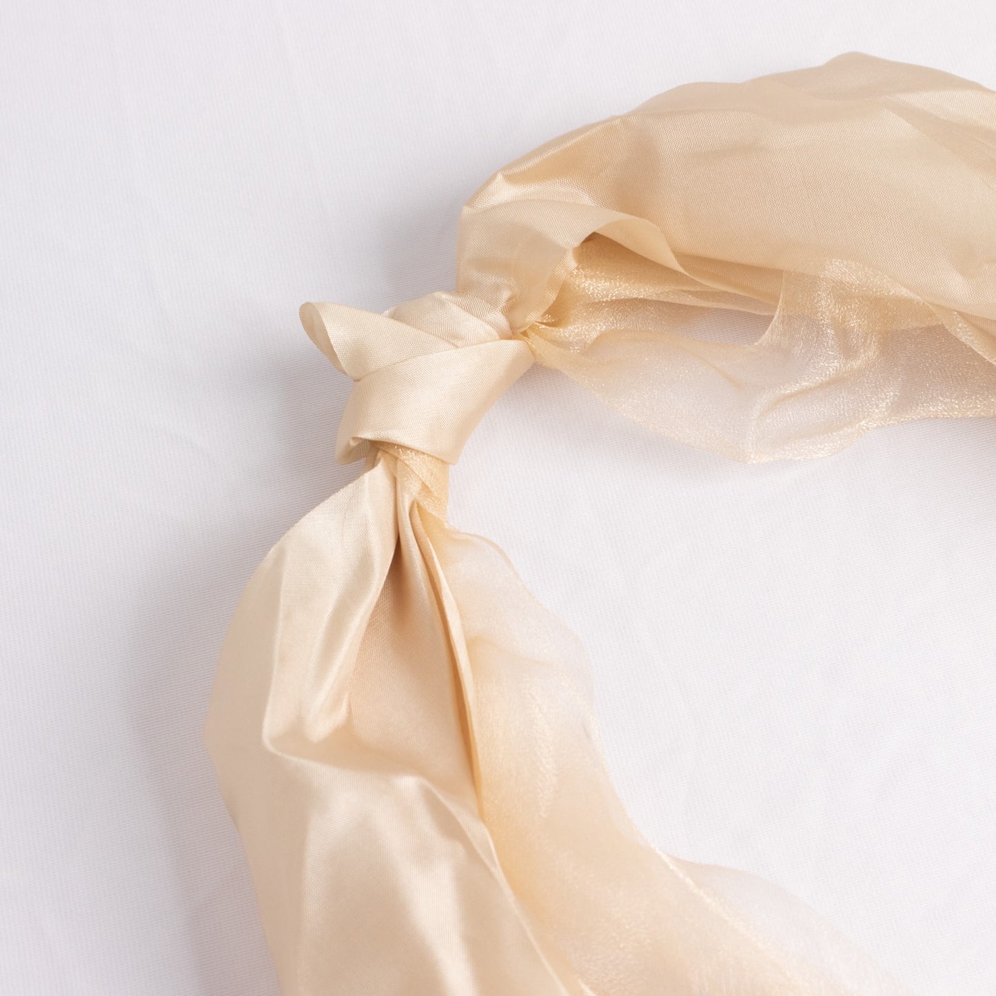Beige chiffon satin chair sash with a curly design.