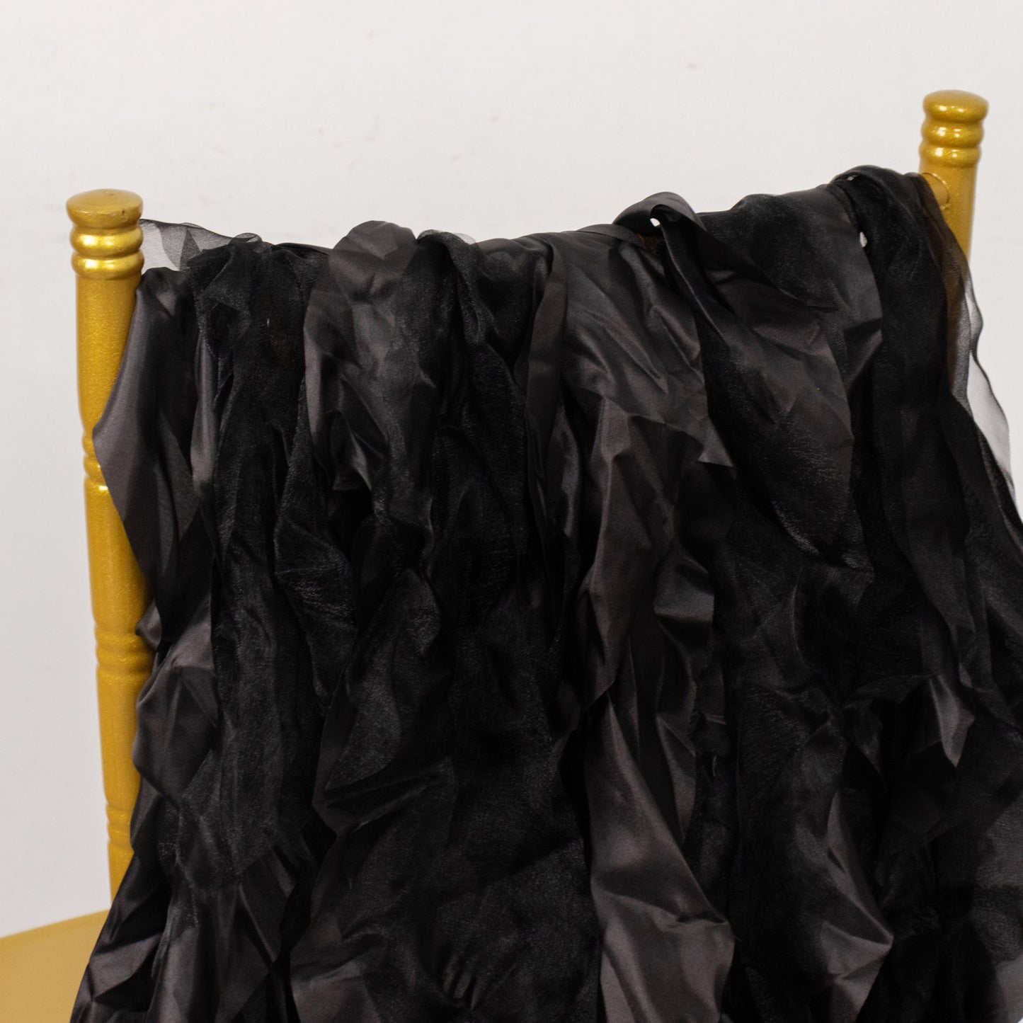 Black curly willow chiffon satin chair sashes draped over a gold chair.