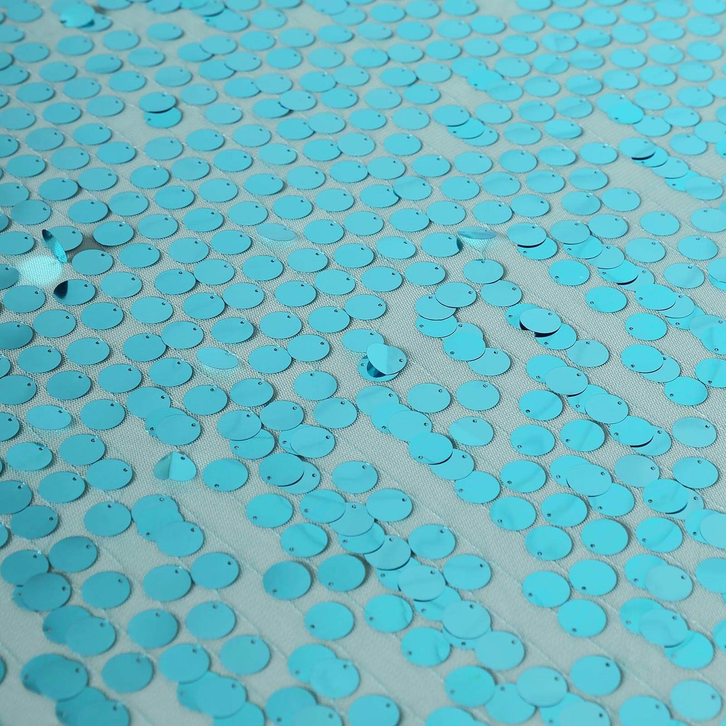 Turquoise sequin tablecloth with a shiny, reflective surface.