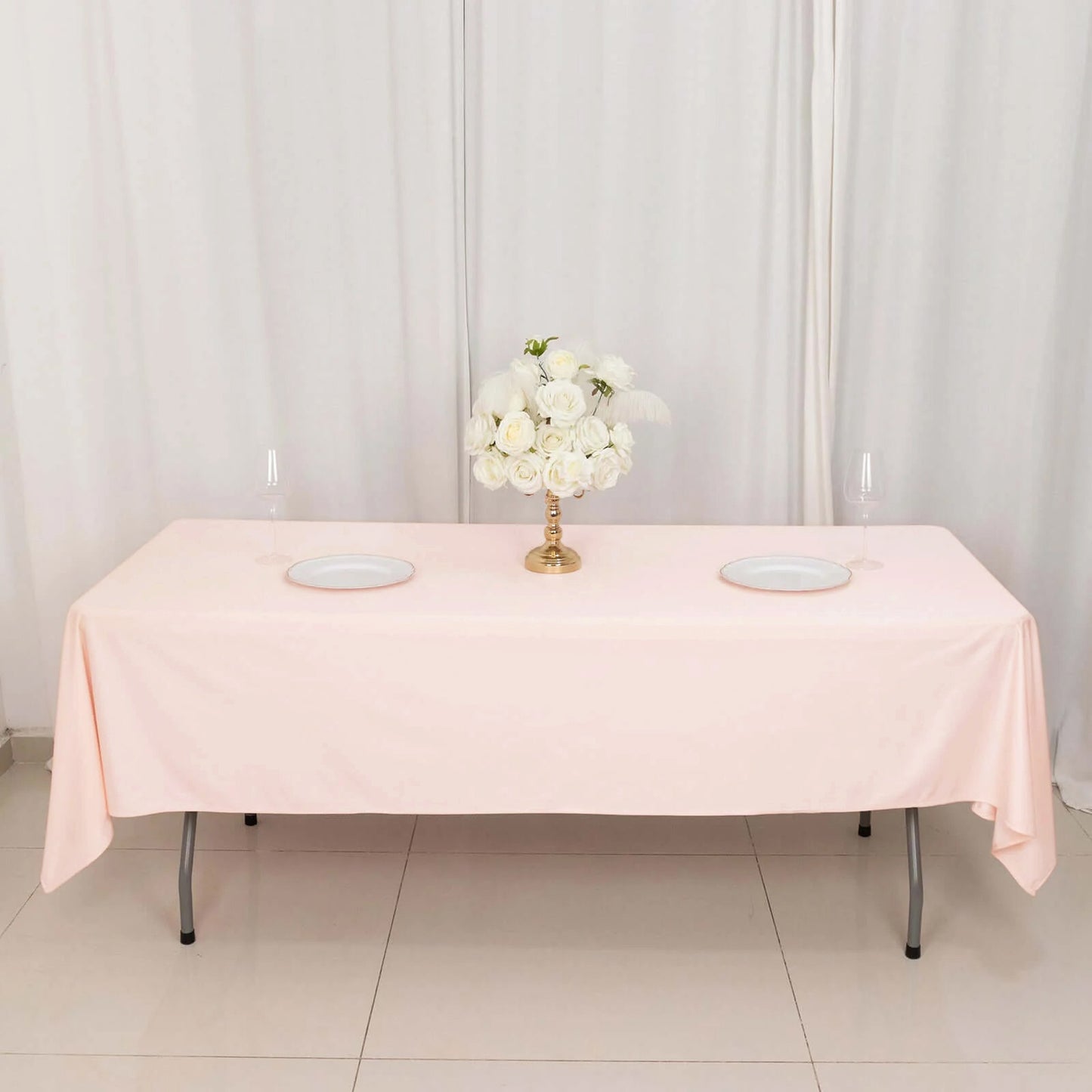 Blush rectangular tablecloth on a dining table with floral centerpiece.