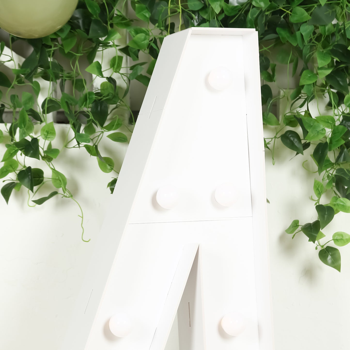 White LED marquee number "4" with warm white lights against greenery.