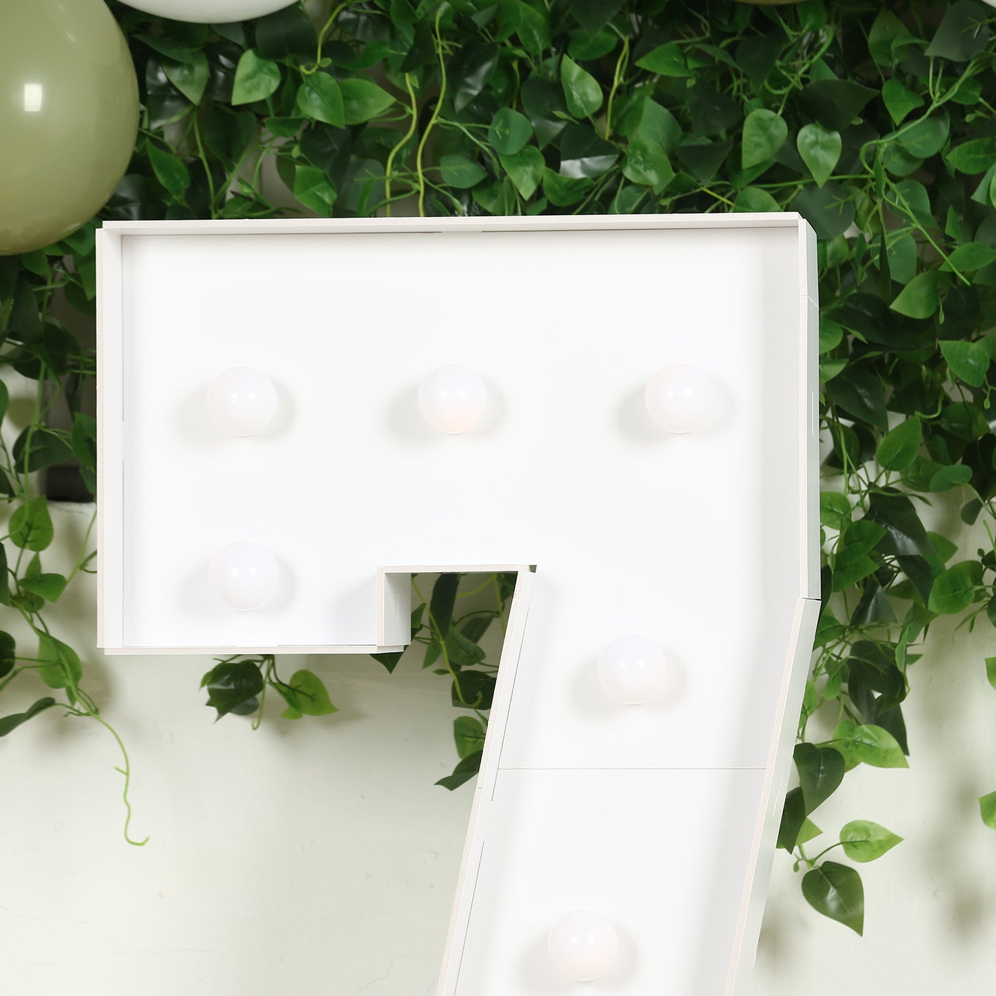 White LED marquee number 7 with warm white lights on a green backdrop.