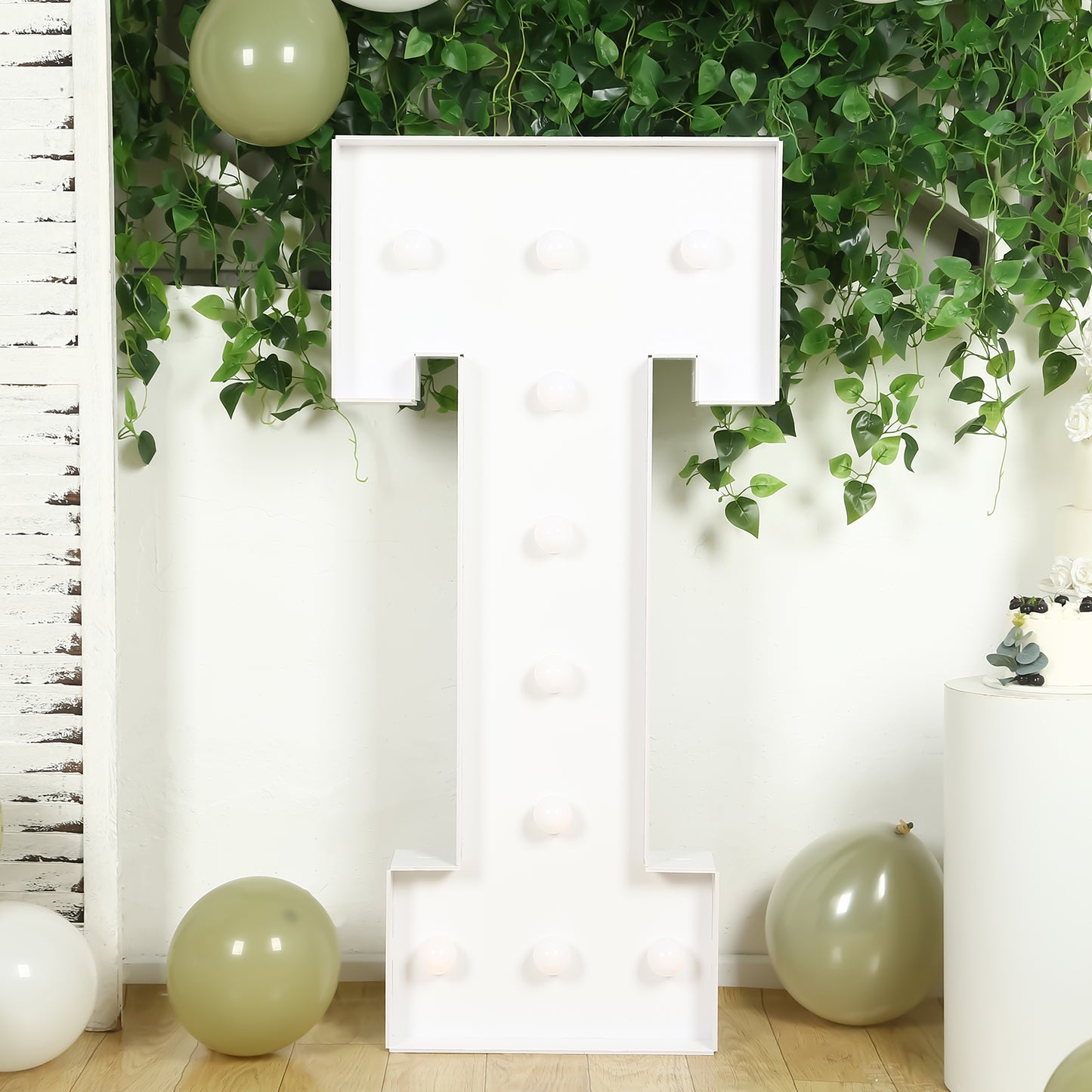 White LED marquee letter "T" with warm white lights in a festive setting.