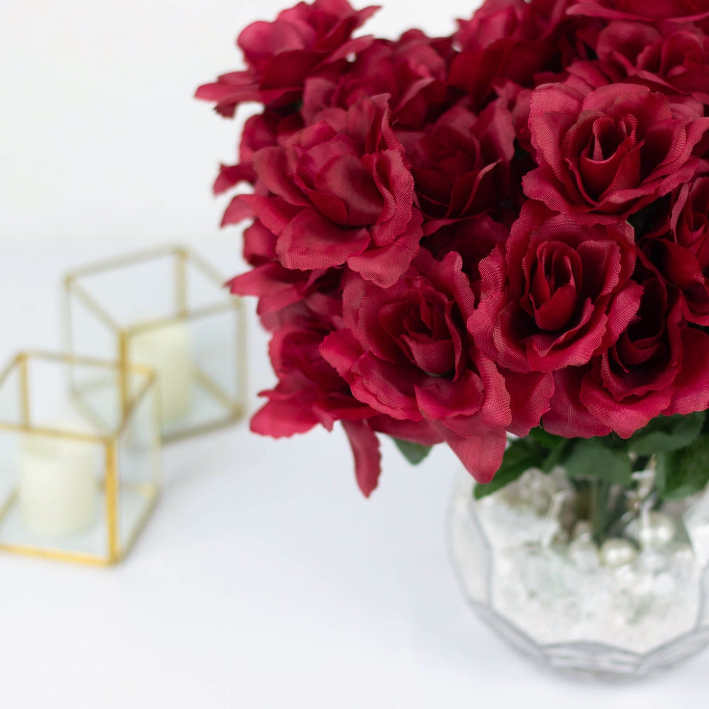 Burgundy artificial silk rose flowers in a vase.