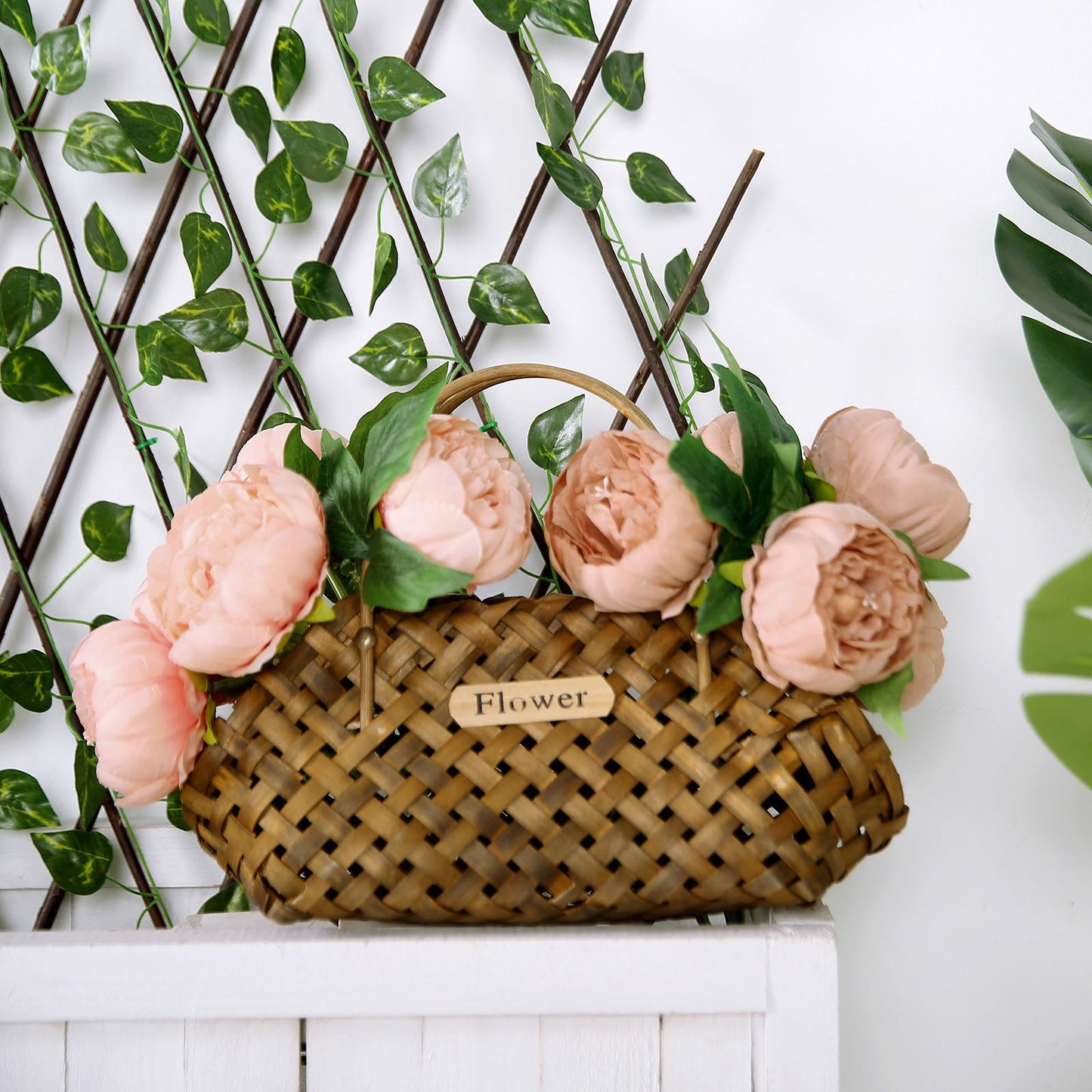 Peach peony bouquet in a woven basket with greenery.
