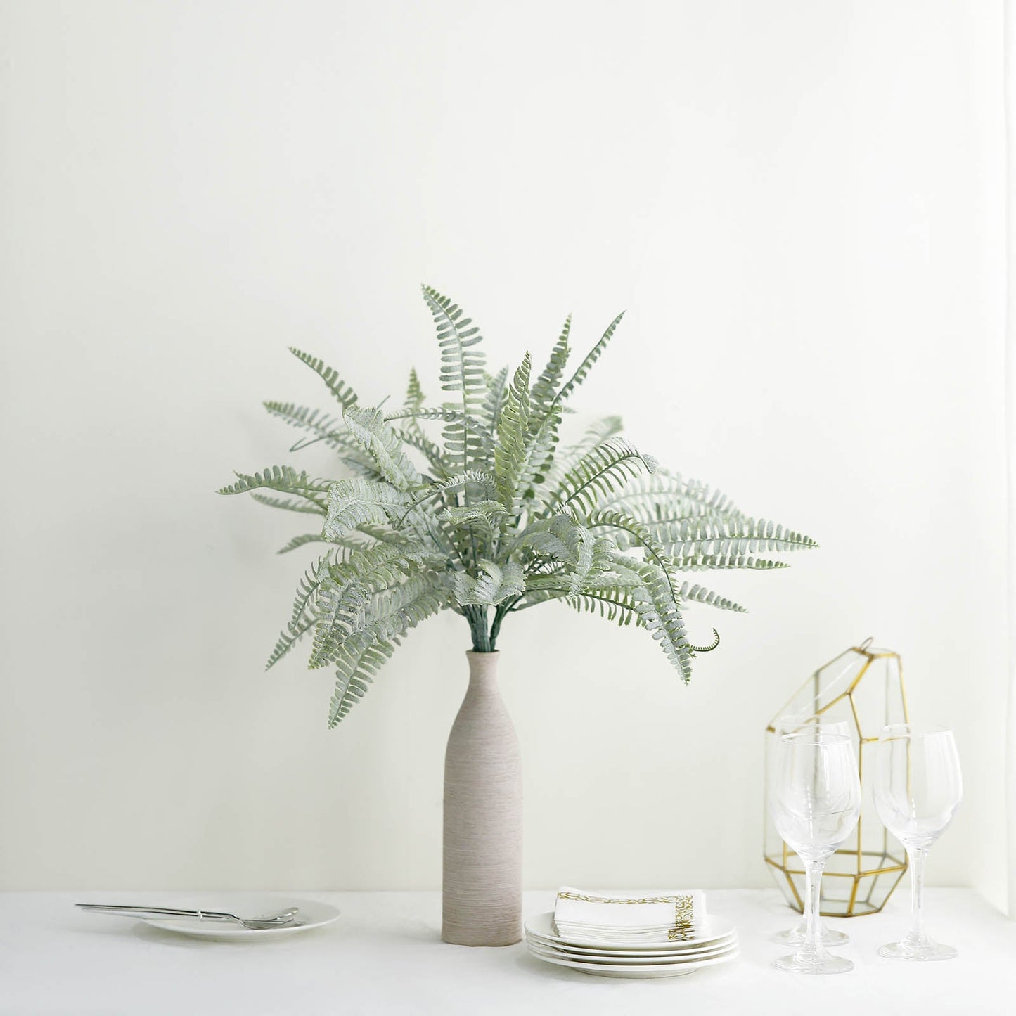 Frosted green artificial Boston fern leaf plant in a vase.