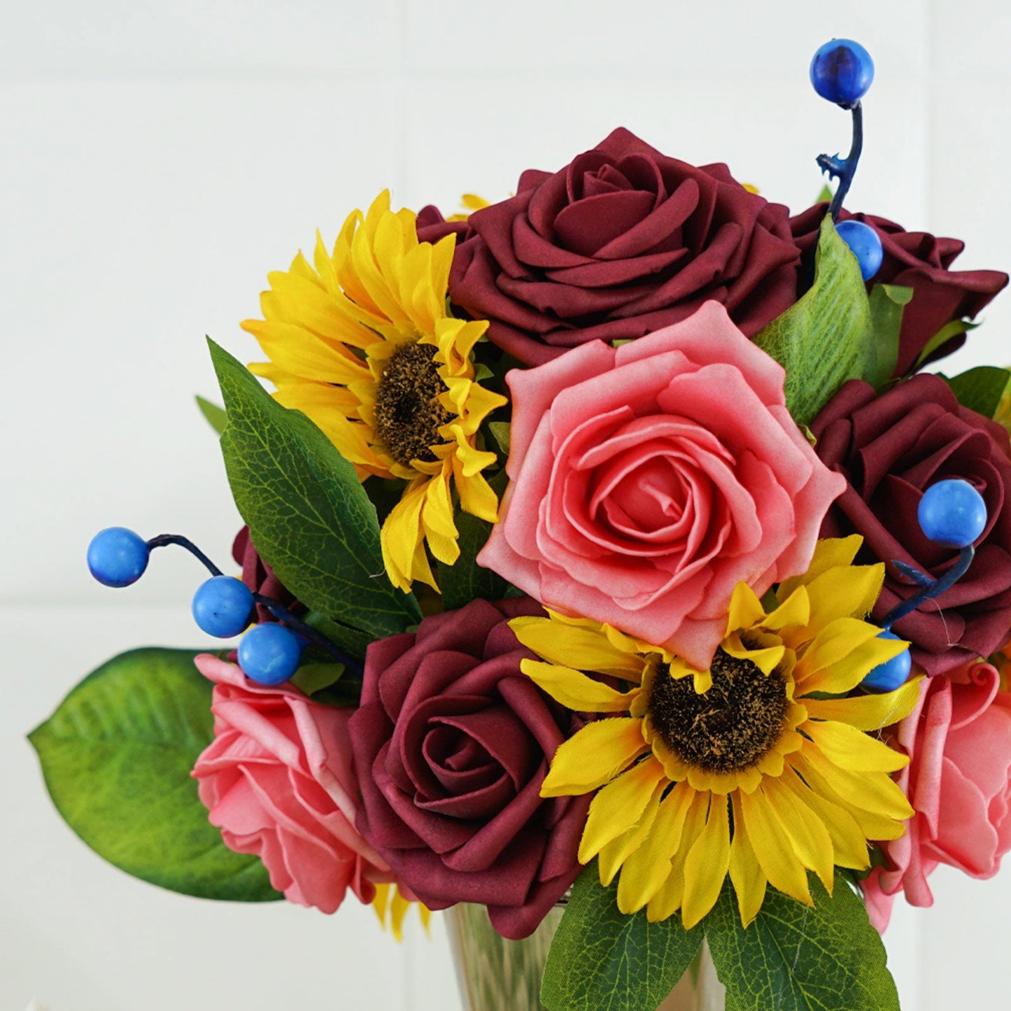 Burgundy and pink artificial flower arrangement with sunflowers and blueberries.