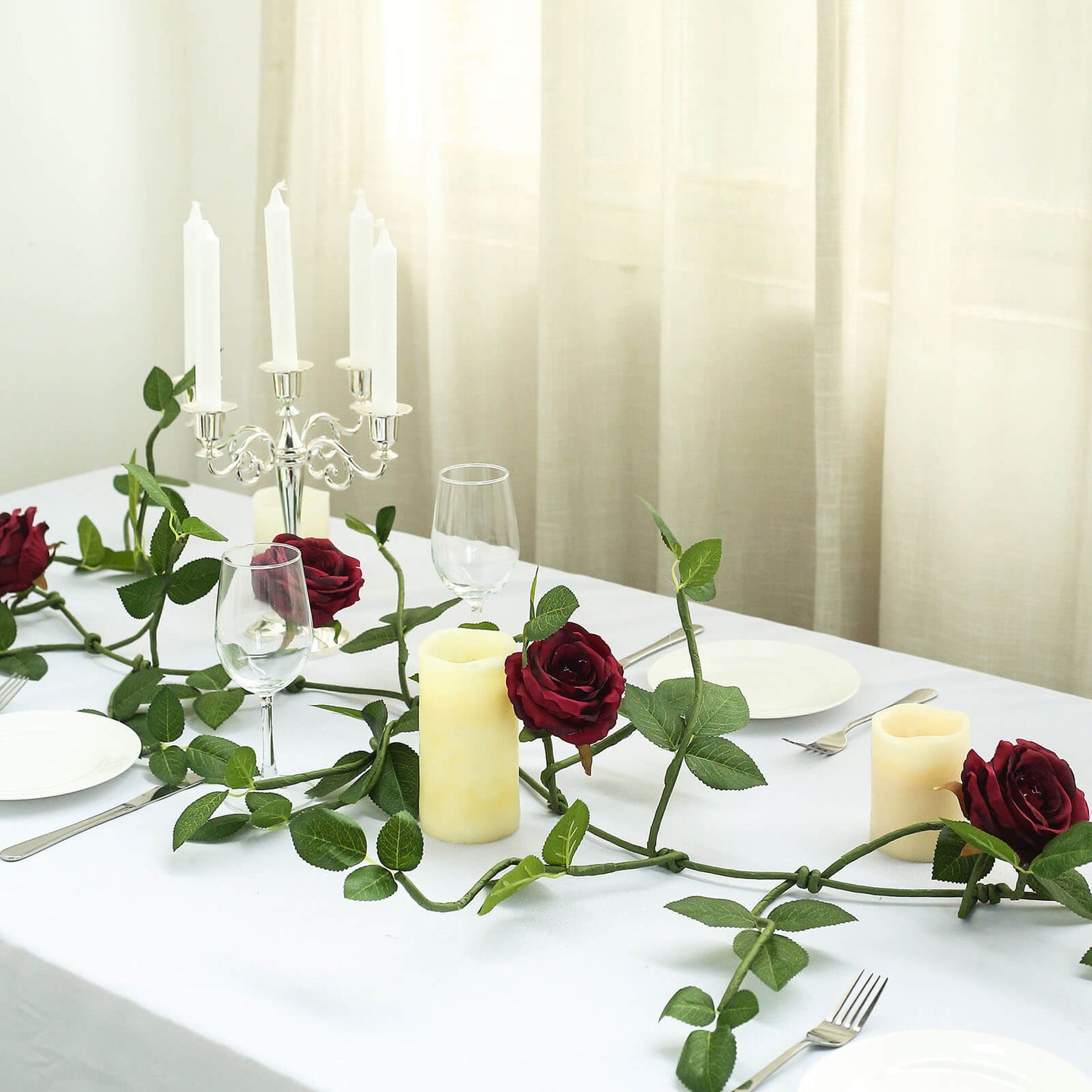 Burgundy real touch artificial rose and leaf garland vine on a table setting.