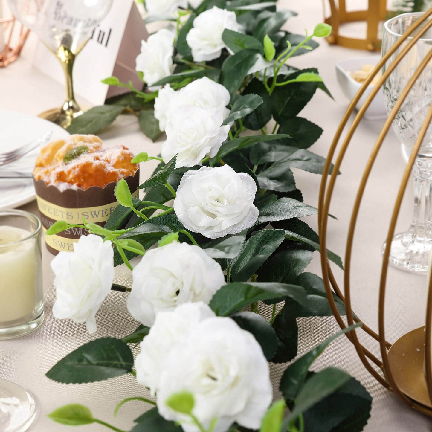 Cream artificial silk roses garland with greenery, perfect for decor.
