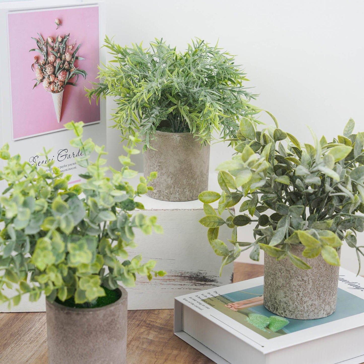 Mini potted artificial eucalyptus, rosemary, and boxwood in green planters.