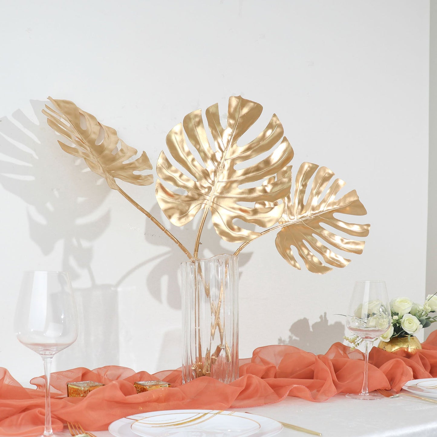 Shiny golden artificial palm leaves in a vase for table centerpiece decor.