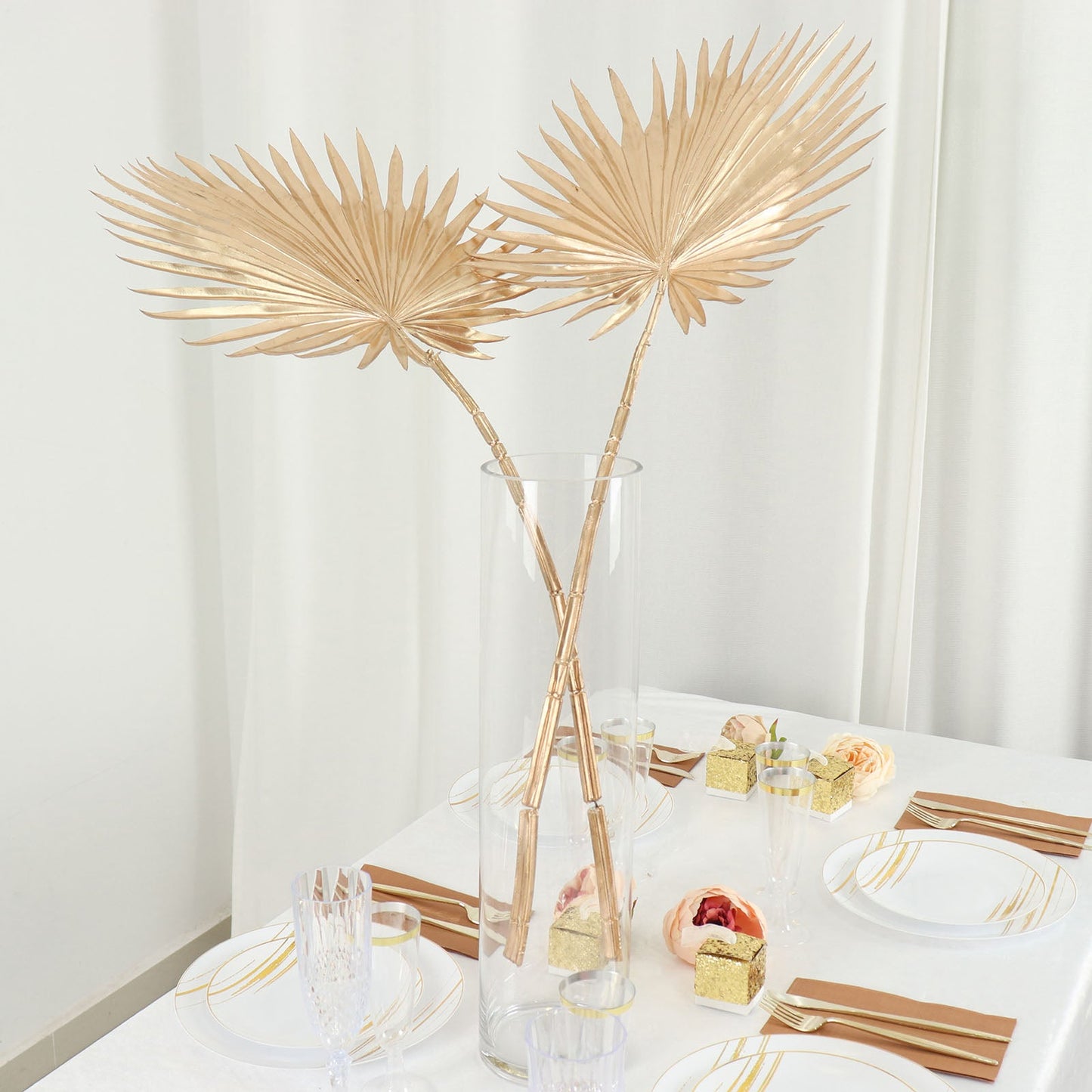 Shiny golden artificial tropical fan palm leaf stems in a vase centerpiece.