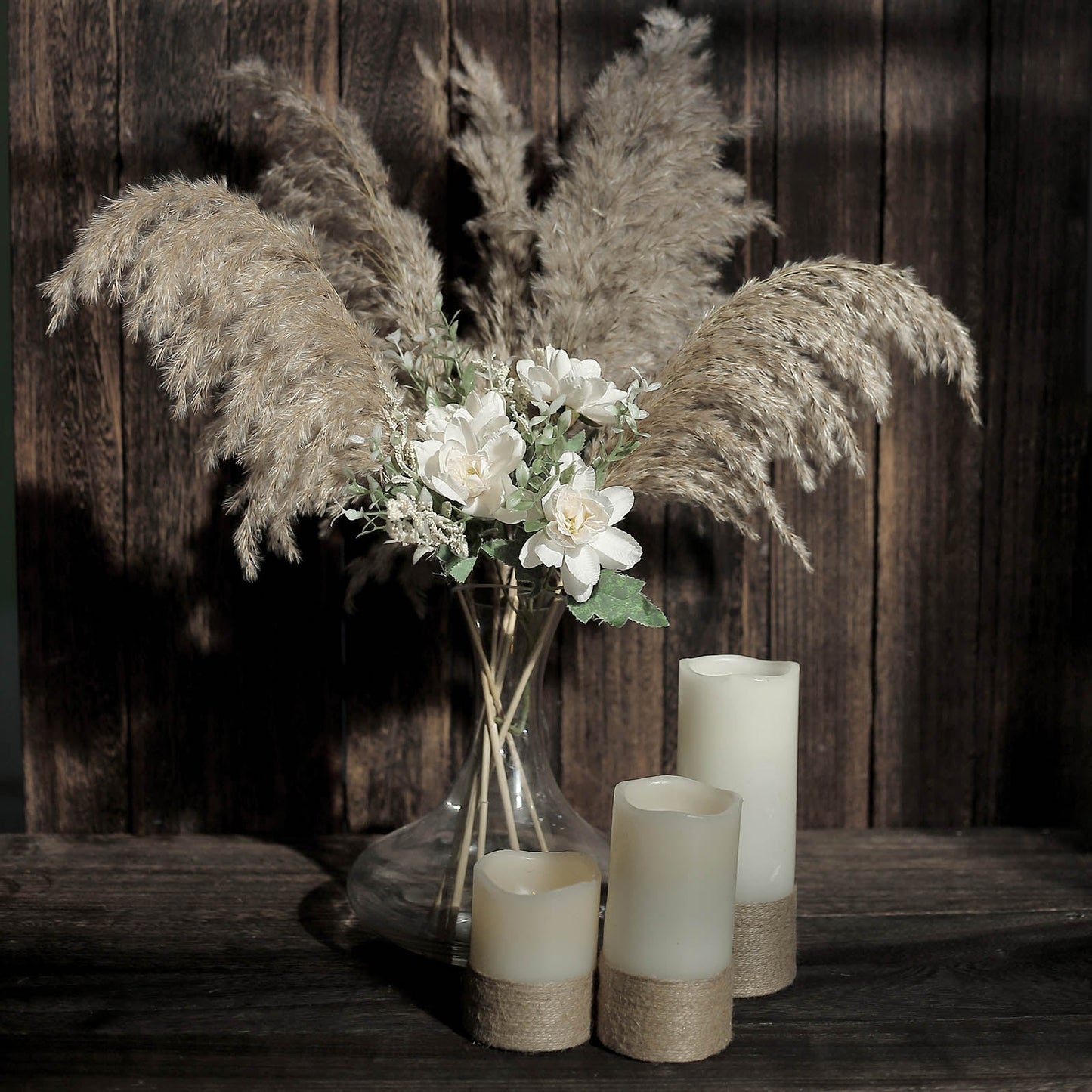 Natural tint dried pampas grass in a vase with white flowers and candles.