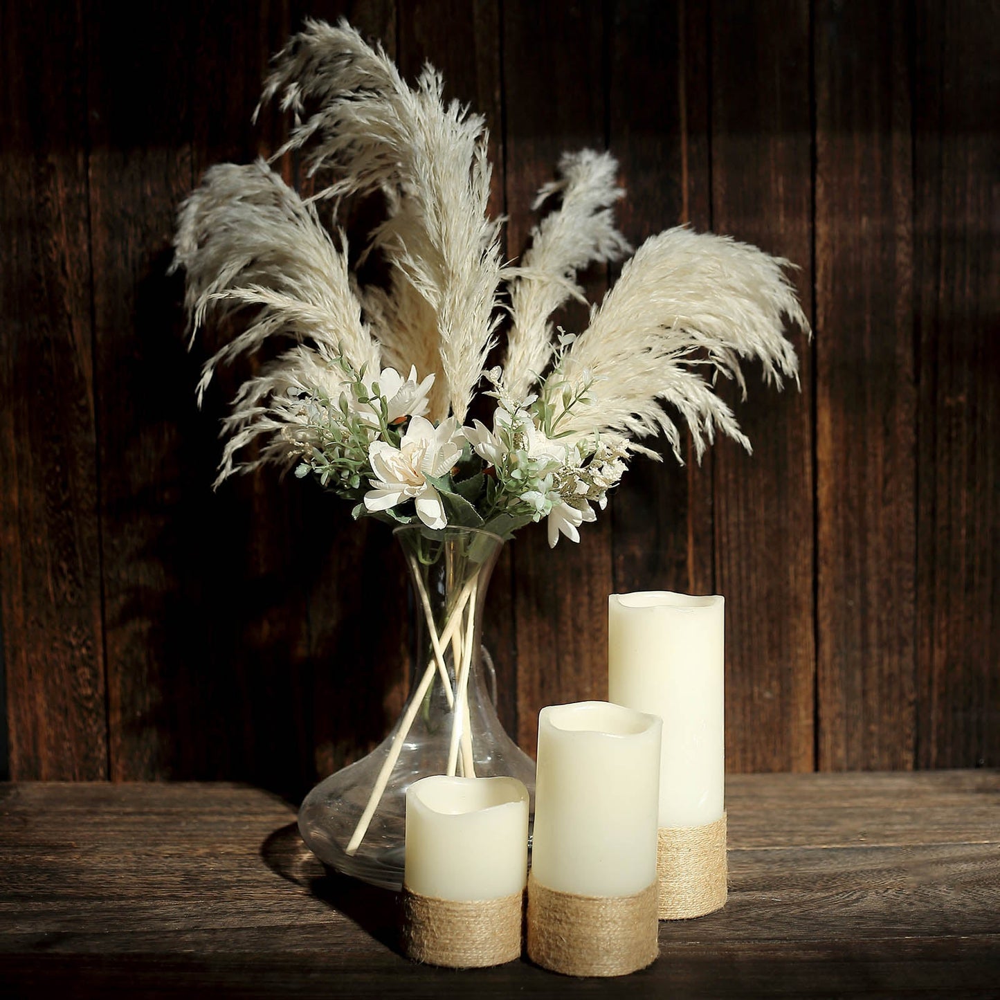 Off white dried pampas grass in a vase with candles.