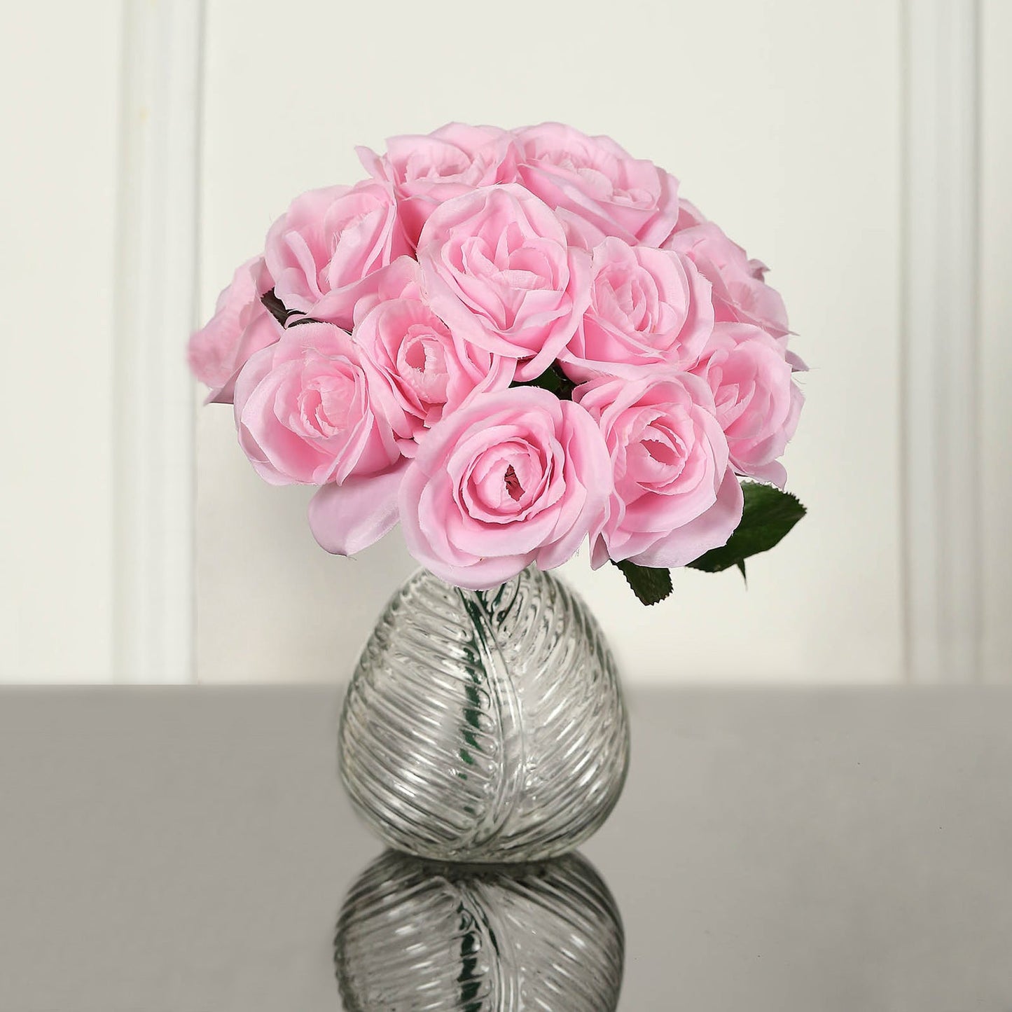 Pink artificial velvet-like rose bouquet in a glass vase.