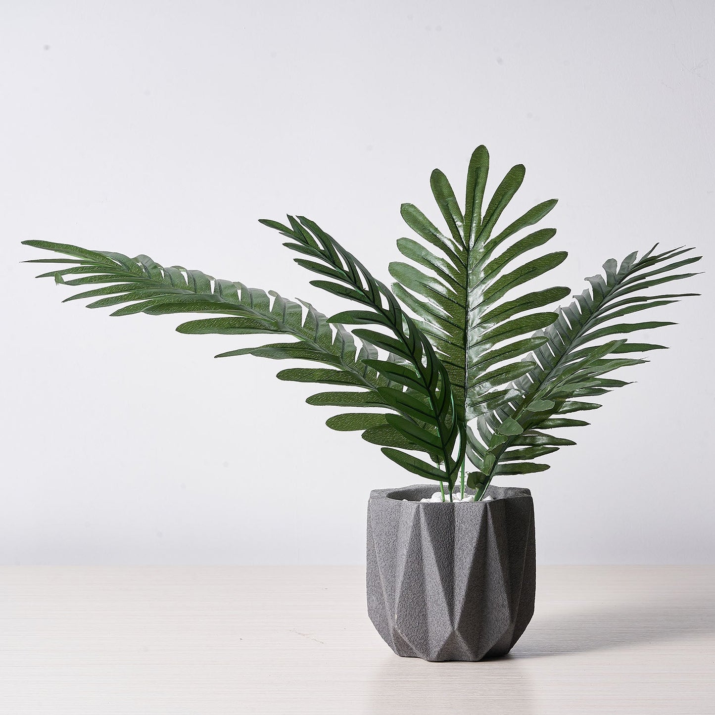 Assorted green artificial silk tropical palm leaf plants in a decorative pot.