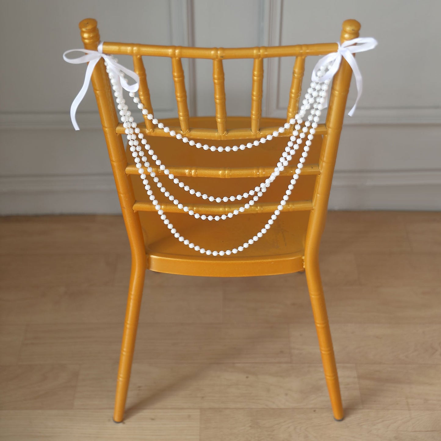 White pearl beaded garland on a Chiavari chair with yellow finish.