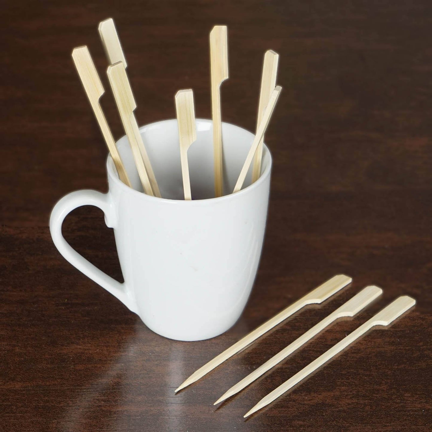 Eco-friendly bamboo skewers in a white mug on a wooden table.