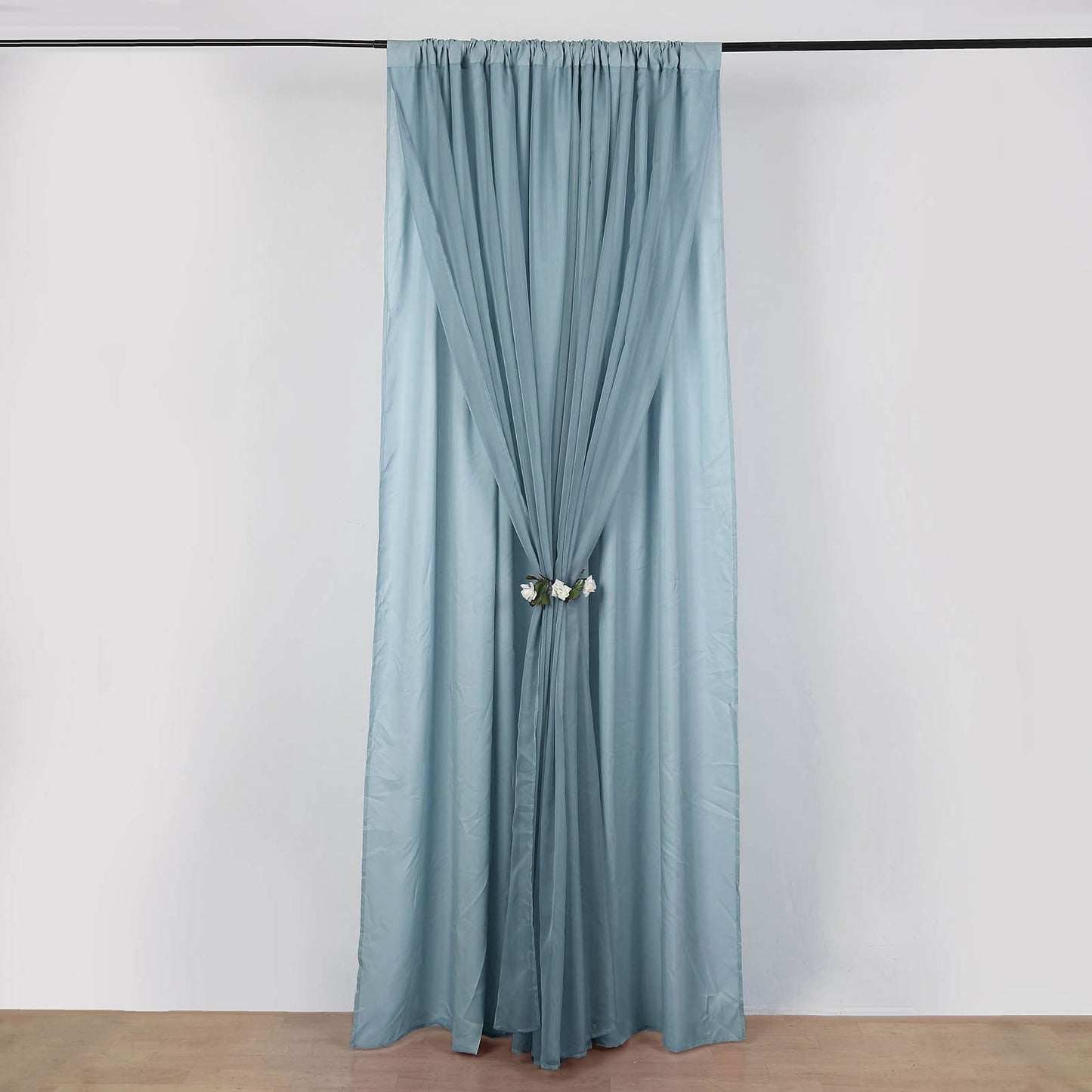 Dusty blue chiffon polyester event curtain drapes hanging in a room.