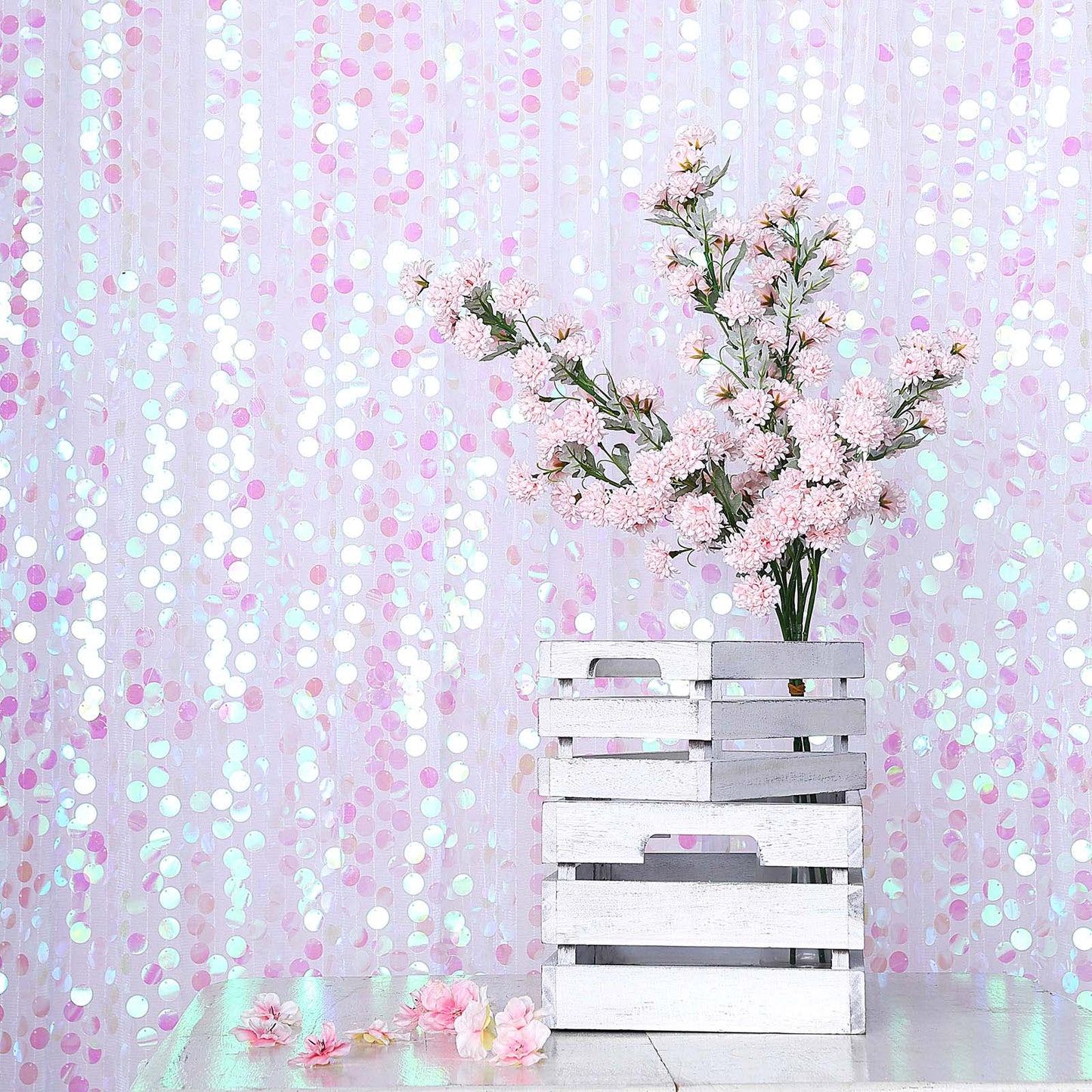 Iridescent big Payette sequin backdrop with pink flowers in a white crate.