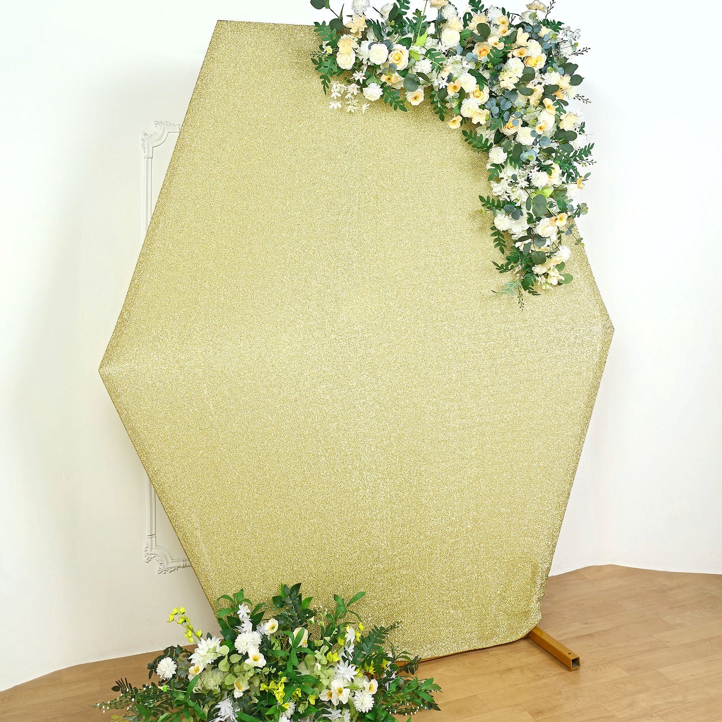 Champagne metallic shimmer tinsel hexagon backdrop with floral accents.