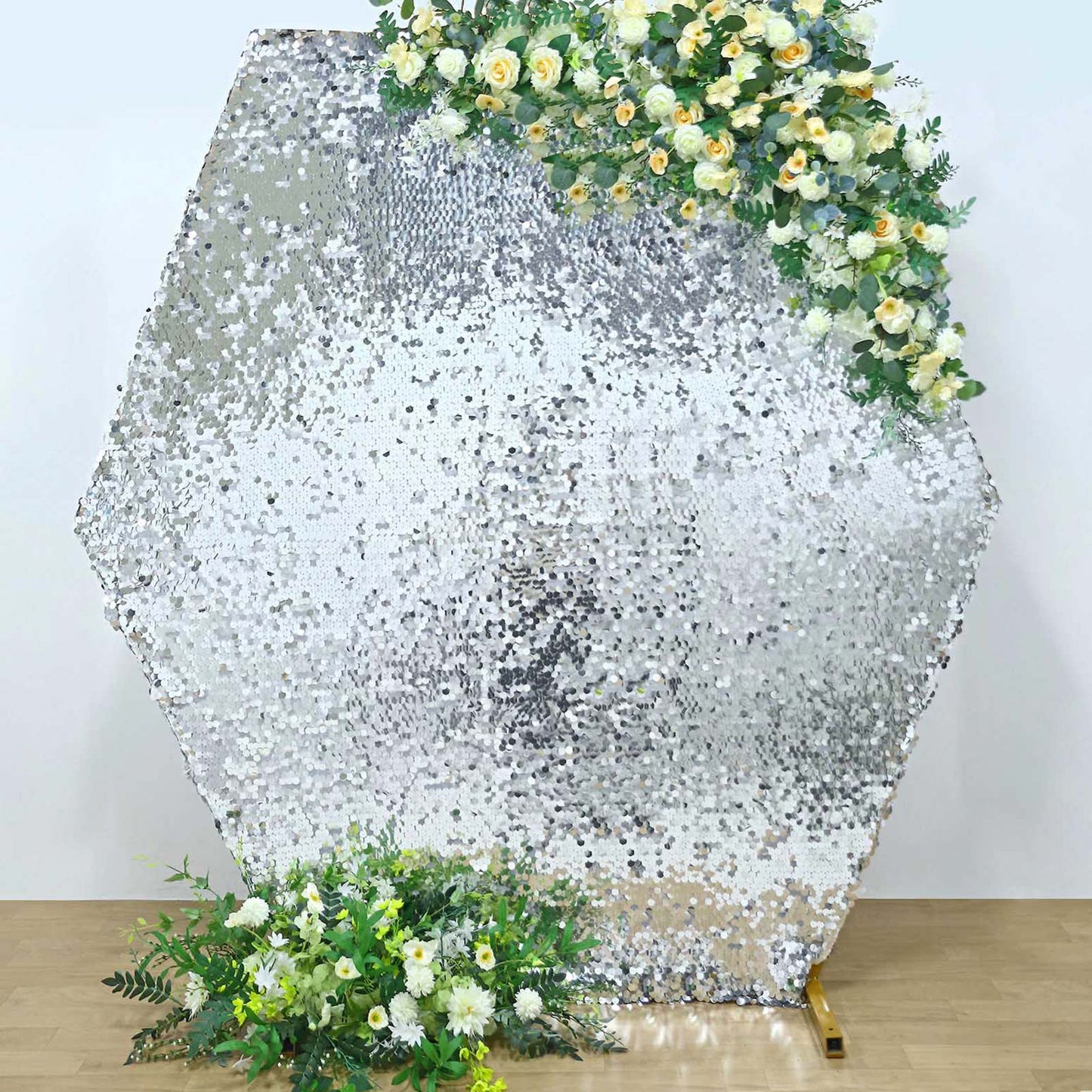 Silver sequin hexagon wedding arch cover with floral arrangement.
