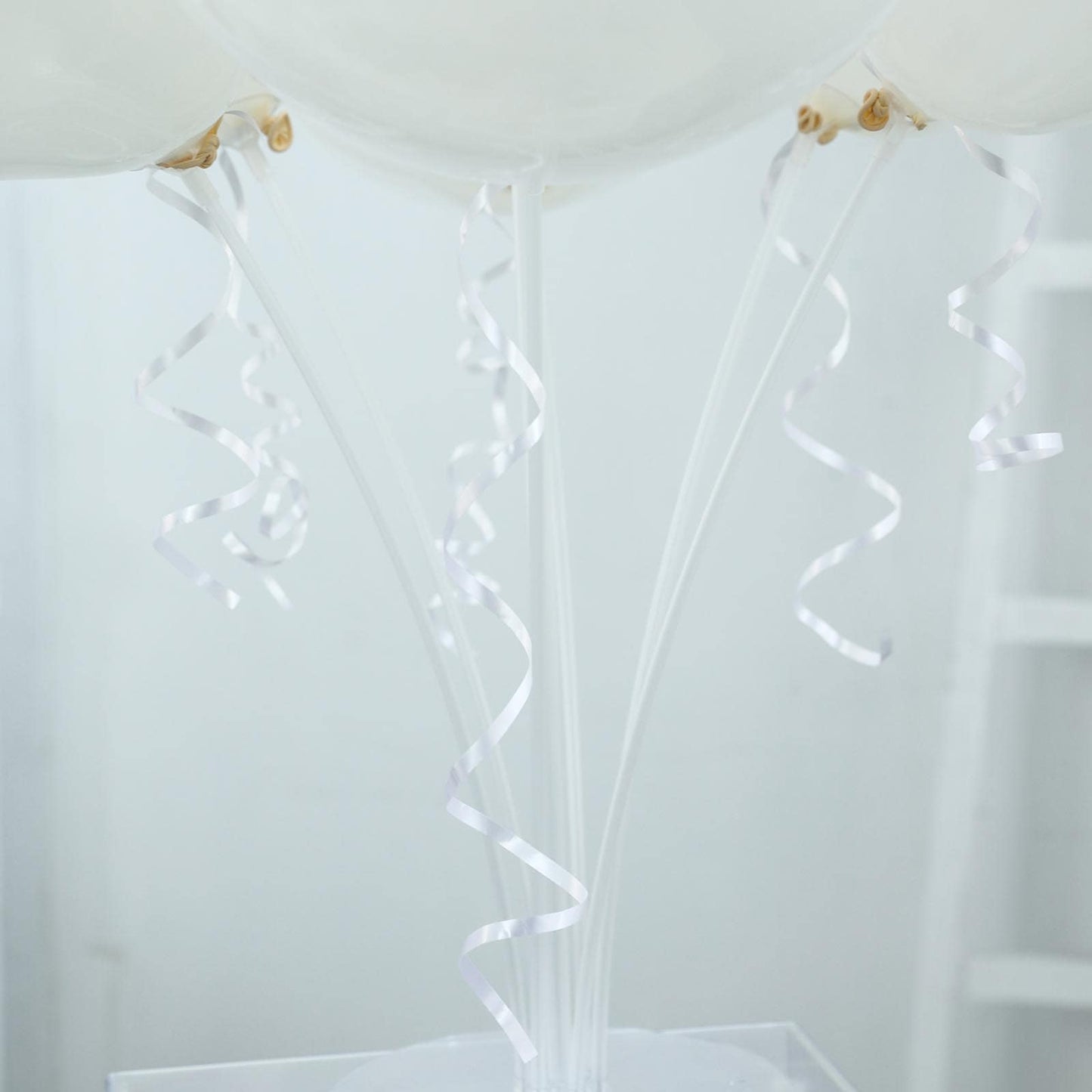 White balloon arch kit with curling ribbons for party decorations.