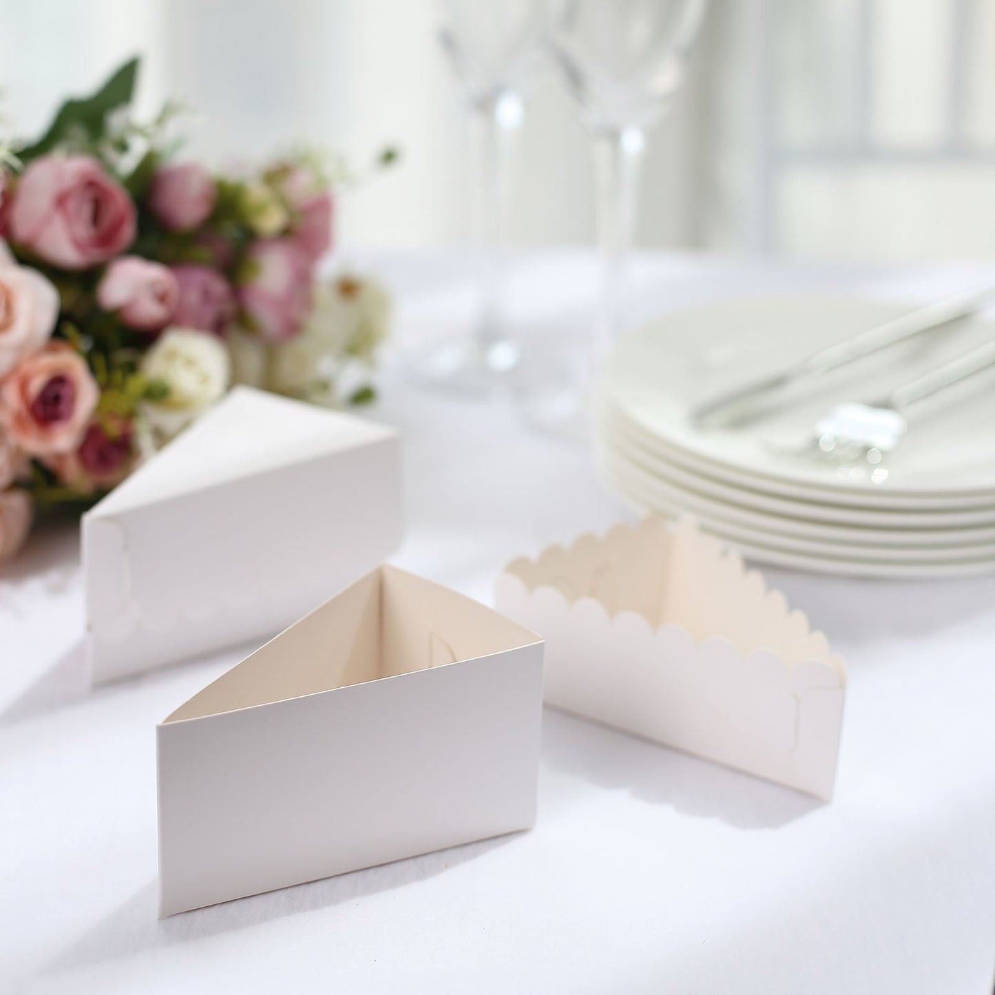White triangular cake boxes with scalloped top for party favors.
